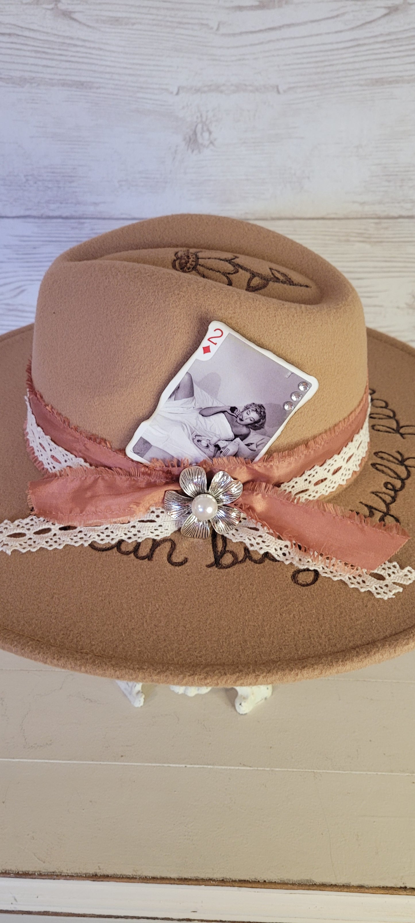 Features "I can by myself flowers" & flowers engraved Frayed rose ribbon, natural lace ribbon with flower brooch & playing card Felt hat Flat brim 65% polyester and 35% cotton Ribbon drawstring for hat size adjustment Head Circumference: 24" Crown Height: 5" Brim Length: 15.75" Brim Width: 14.5" Branded & numbered inside crown Custom burned & engraved by Kayla