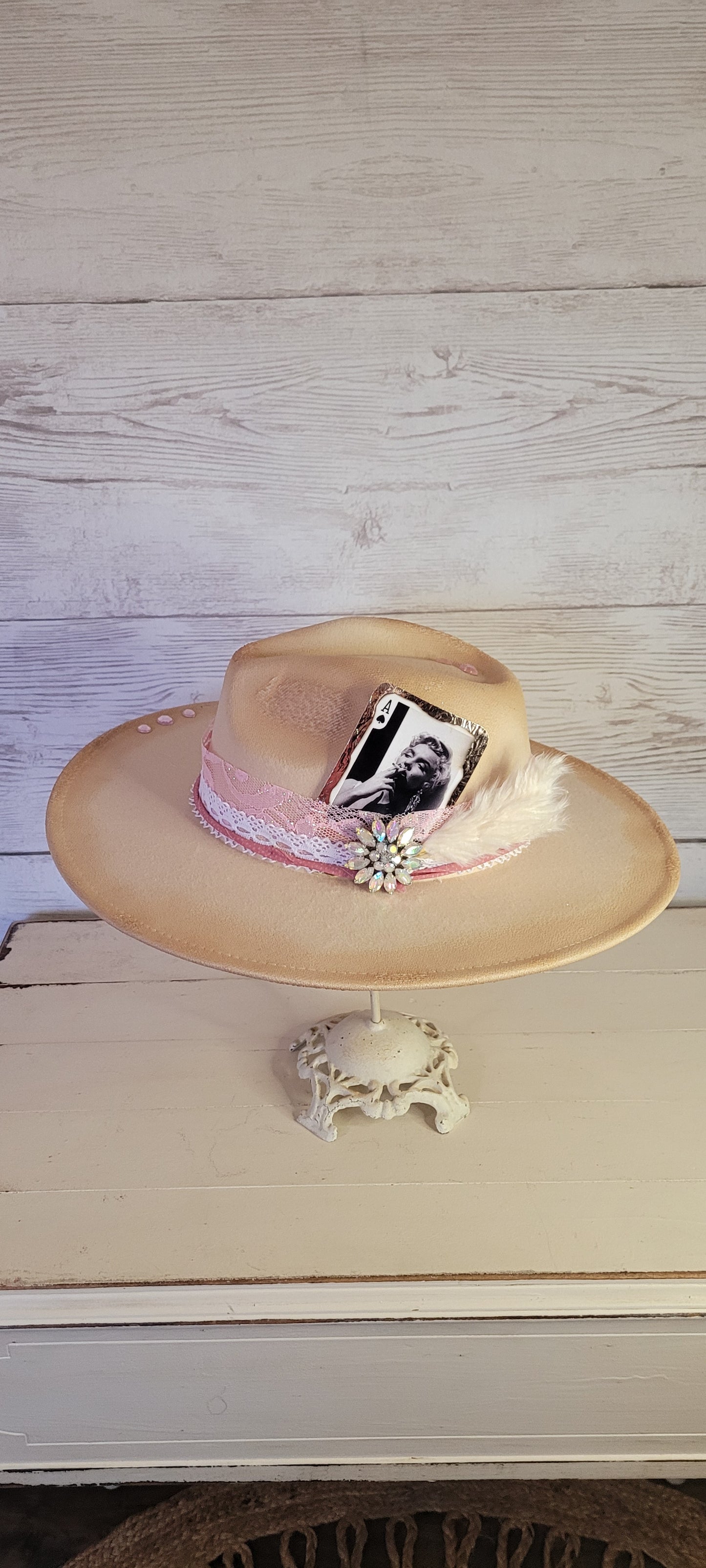 Pink ribbon & lace, natural lace ribbon, pampas, AB rhinestone brooch, light pink rhinestones & playing card Felt hat Flat brim 65% polyester and 35% cotton Ribbon drawstring for hat size adjustment Head Circumference: 24" Crown Height: 5" Brim Length: 15.75" Brim Width: 14.5" Branded & numbered inside crown Custom burned & designed by Kayla
