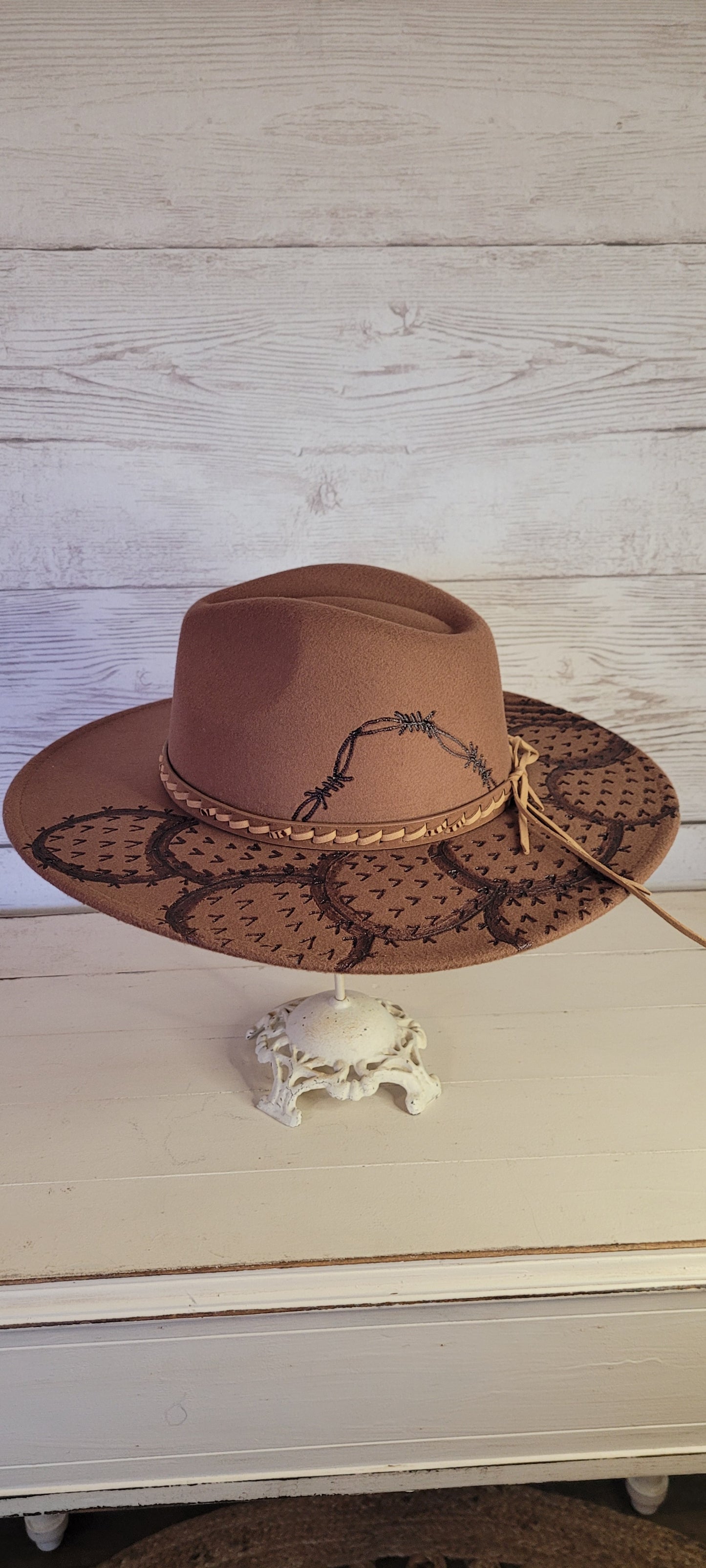 Features barbwire, cactus & saguaro Natural lace ribbon & leather band Felt hat Flat brim 100% polyester Ribbon drawstring for hat size adjustment Head Circumference: 24" Crown Height: 5" Brim Length: 15.75" Brim Width: 14.5" Branded & numbered inside crown Custom engraved by Kayla