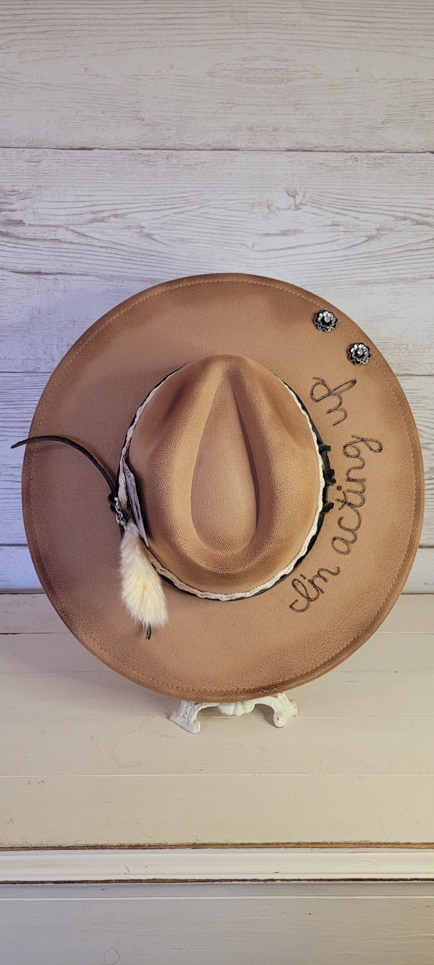 Features "I'm acting up" engraving Lace ribbon, leather band, pampas, rhinestone brooches, playing card Felt hat Flat brim 100% polyester Ribbon drawstring for hat size adjustment Head Circumference: 24" Crown Height: 5" Brim Length: 15.75" Brim Width: 14.5" Branded & numbered inside crown Custom burned & engraved by Kayla