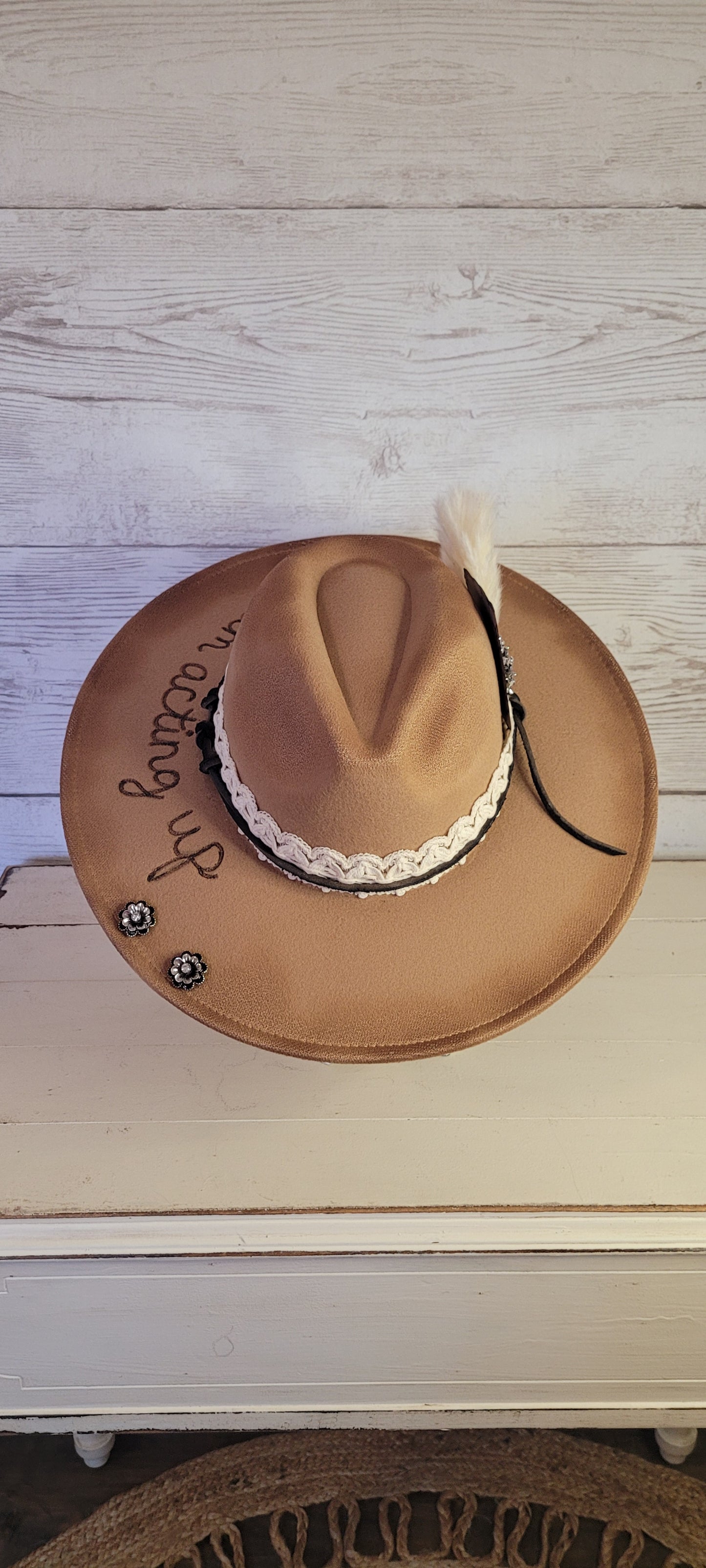 Features "I'm acting up" engraving Lace ribbon, leather band, pampas, rhinestone brooches, playing card Felt hat Flat brim 100% polyester Ribbon drawstring for hat size adjustment Head Circumference: 24" Crown Height: 5" Brim Length: 15.75" Brim Width: 14.5" Branded & numbered inside crown Custom burned & engraved by Kayla