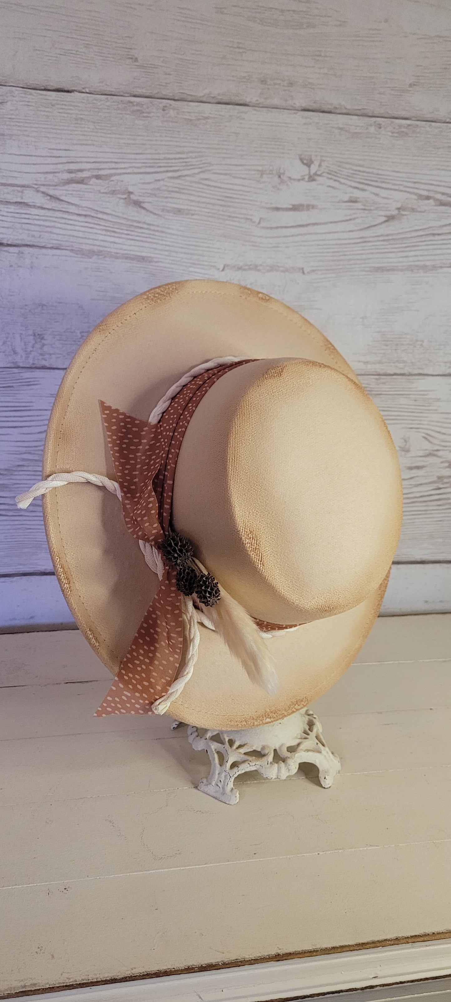 Sheer ribbon, natural gauze rope, pine cones & pampas Felt hat Flat brim 100% polyester Ribbon drawstring for hat size adjustment Head Circumference: 24" Crown Height: 3.5" Brim Length: 13.5" Brim Width: 12.75" Branded & numbered inside crown Custom burned by Kayla