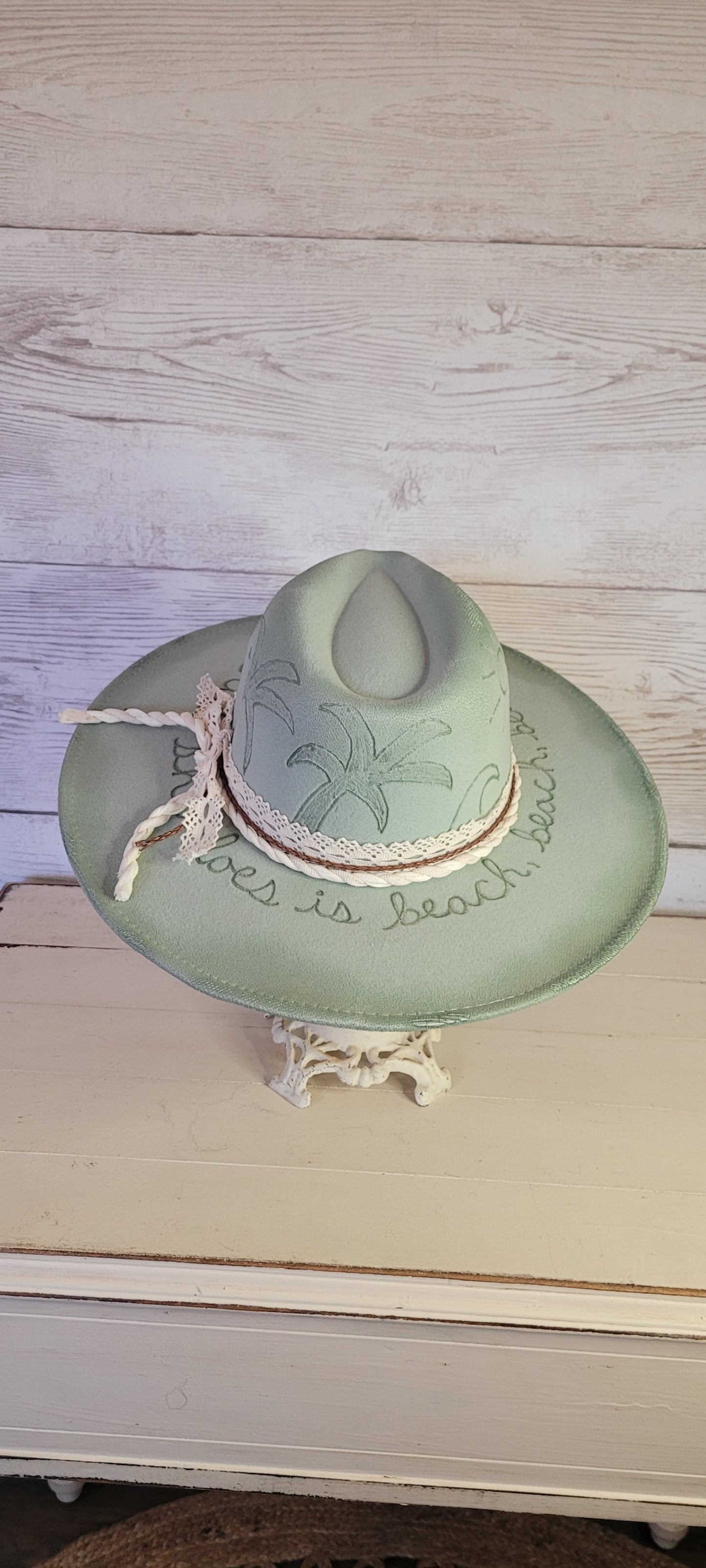Features sunshine, palm trees, waves & "all she does is beach, beach, beach" engraved Lace ribbon, brown cord, & natural gauze rope Felt hat Flat brim 65% polyester and 35% cotton Ribbon drawstring for hat size adjustment Head Circumference: 24" Crown Height: 5" Brim Length: 15.75" Brim Width: 14.5" Branded & numbered inside crown Custom burned & engraved by Kayla