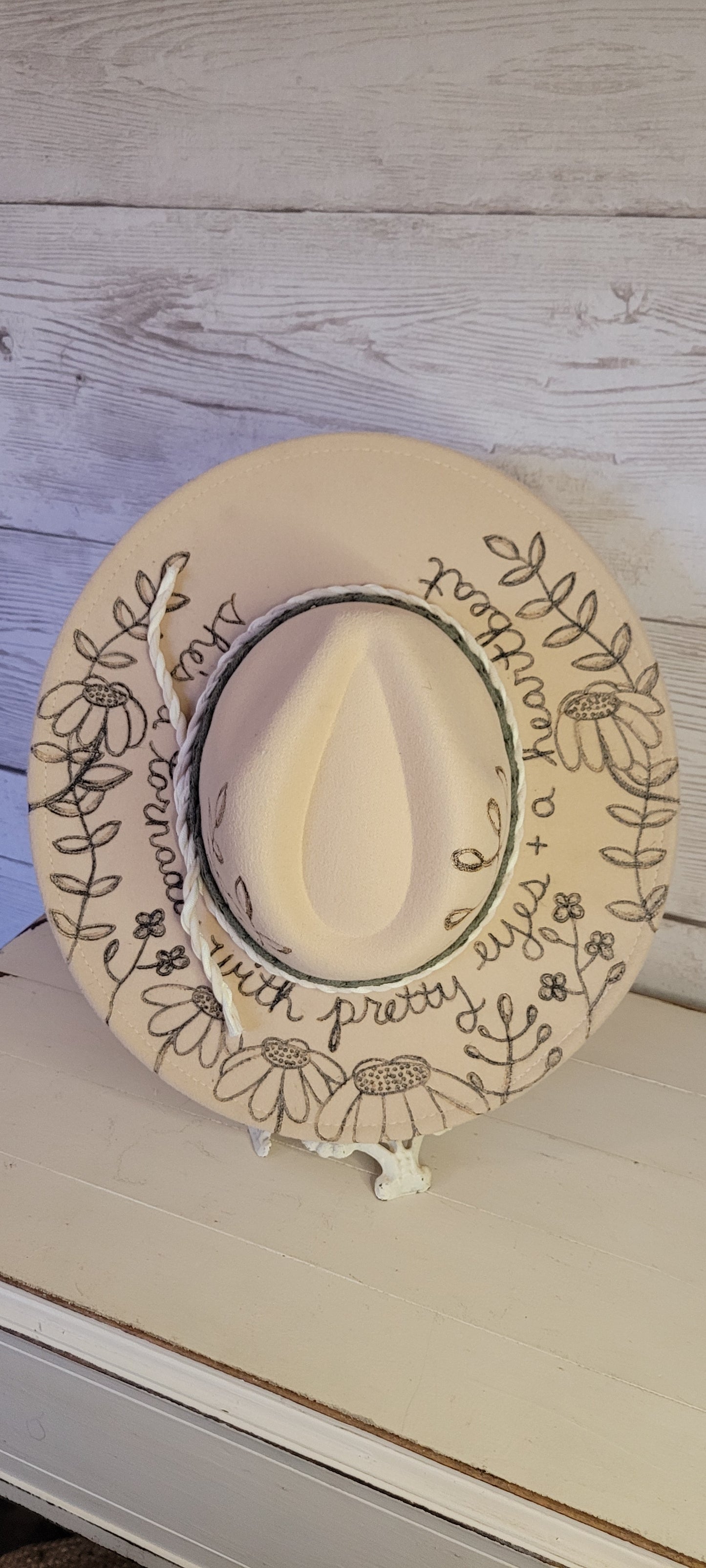 Features engraved whimsical flowers & plants Felt hat Flat brim 65% polyester and 35% cotton Ribbon drawstring for hat size adjustment Head Circumference: 25" H:5.25" L:16" W:14.5" Head Circumference: 24" Crown Height: 5" Brim Length: 15.75" Brim Width: 14.5" Branded & numbered inside crown Custom engraved by Kayla