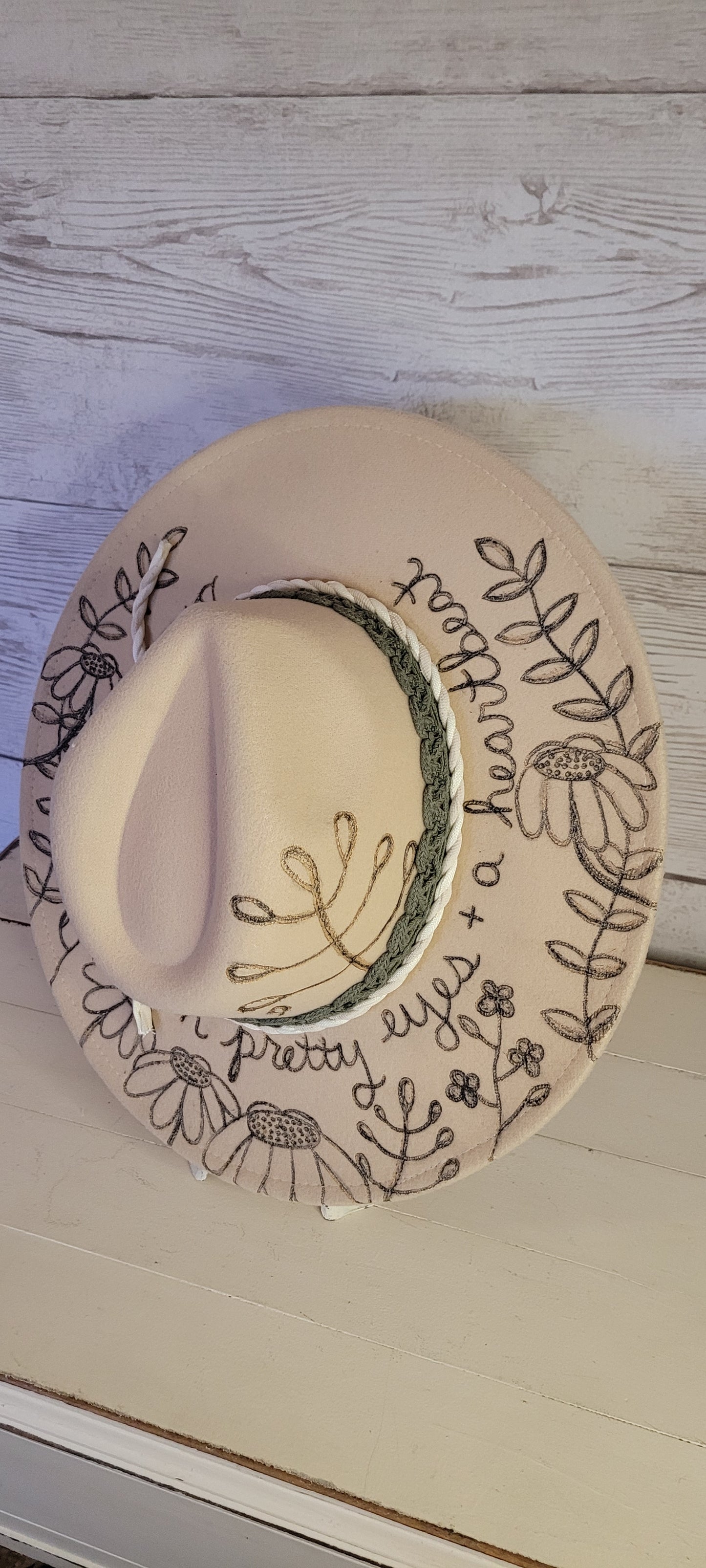 Features engraved whimsical flowers & plants Felt hat Flat brim 65% polyester and 35% cotton Ribbon drawstring for hat size adjustment Head Circumference: 25" H:5.25" L:16" W:14.5" Head Circumference: 24" Crown Height: 5" Brim Length: 15.75" Brim Width: 14.5" Branded & numbered inside crown Custom engraved by Kayla