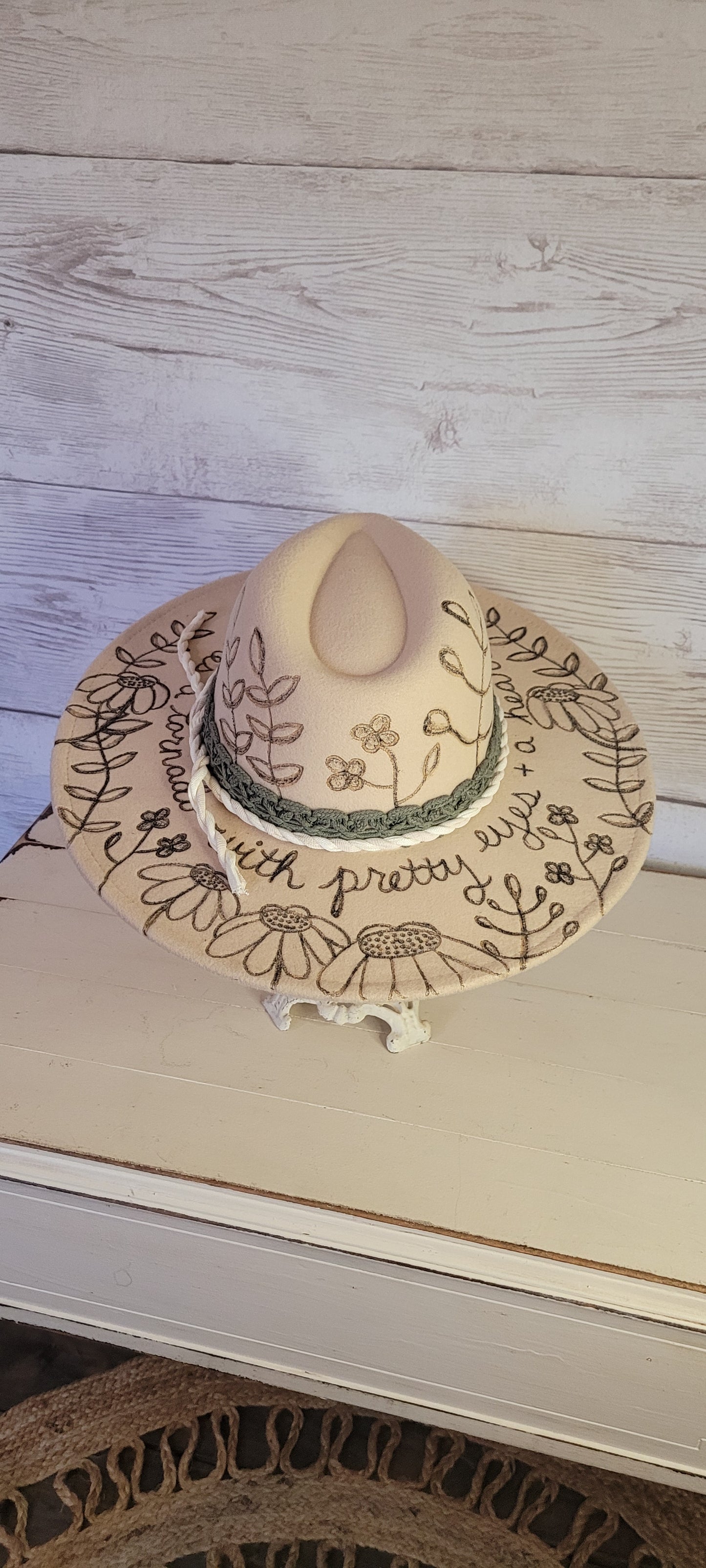 Features engraved whimsical flowers & plants Felt hat Flat brim 65% polyester and 35% cotton Ribbon drawstring for hat size adjustment Head Circumference: 25" H:5.25" L:16" W:14.5" Head Circumference: 24" Crown Height: 5" Brim Length: 15.75" Brim Width: 14.5" Branded & numbered inside crown Custom engraved by Kayla