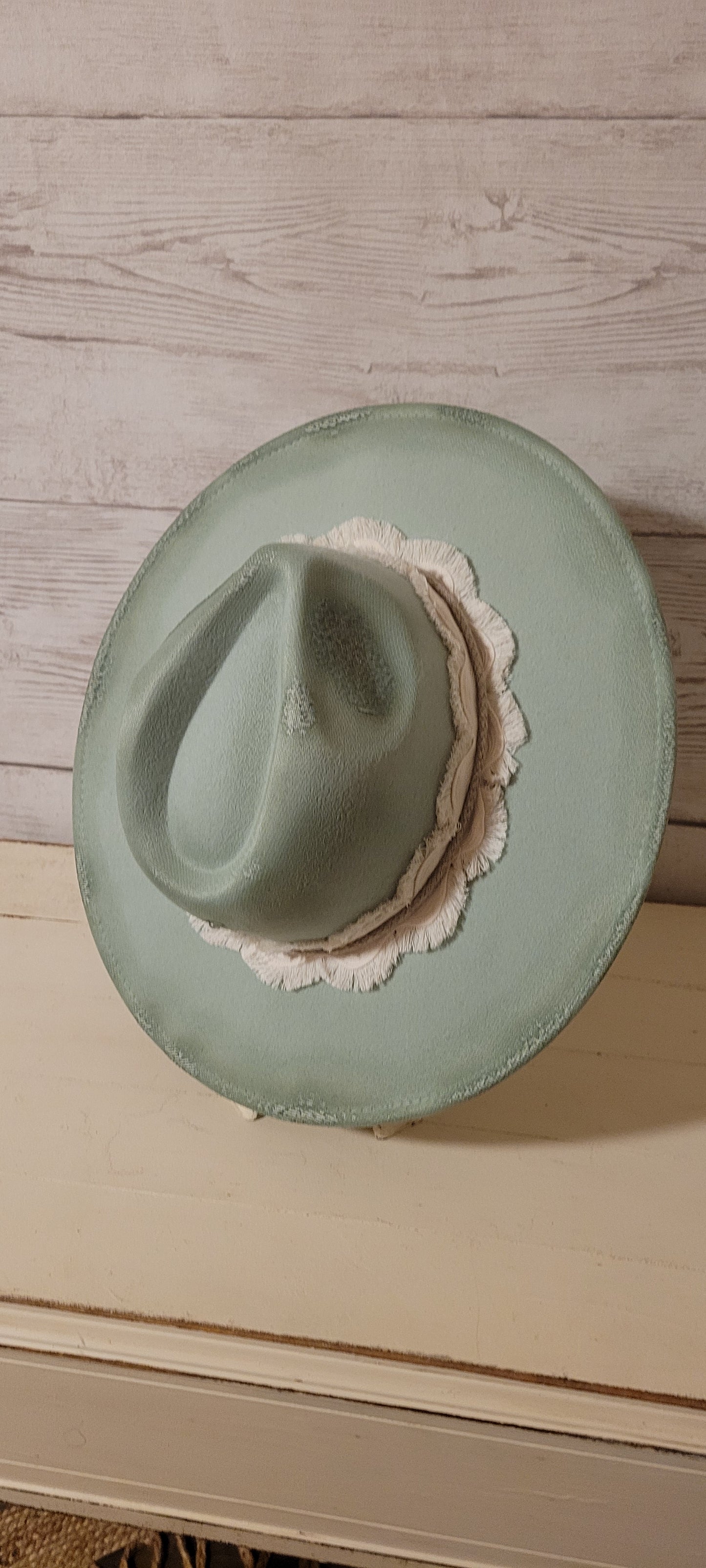 Features flowers engraved Wavy frayed ribbon, natural cord, rhinestones & metal pearl brooch Felt hat Flat brim 100% polyester Ribbon drawstring for hat size adjustment Head Circumference: 24" Crown Height: 5" Brim Length: 15.75" Brim Width: 14.5" Branded & numbered inside crown Custom burned & engraved by Kayla