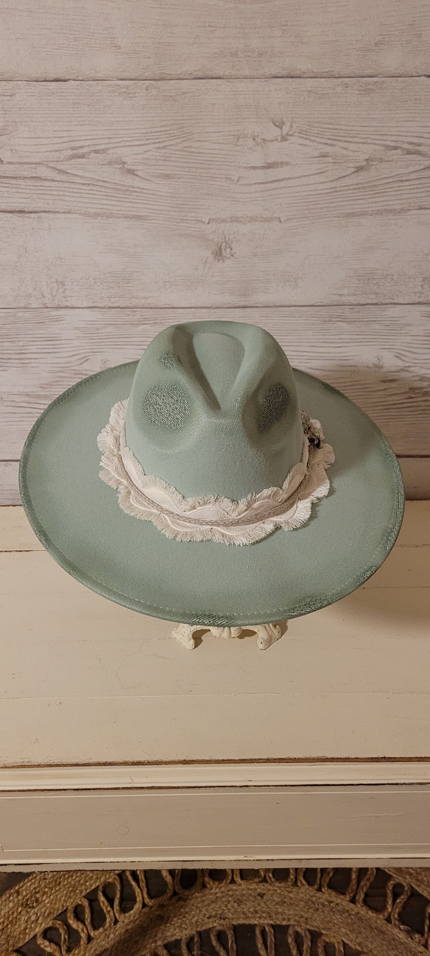 Features flowers engraved Wavy frayed ribbon, natural cord, rhinestones & metal pearl brooch Felt hat Flat brim 100% polyester Ribbon drawstring for hat size adjustment Head Circumference: 24" Crown Height: 5" Brim Length: 15.75" Brim Width: 14.5" Branded & numbered inside crown Custom burned & engraved by Kayla