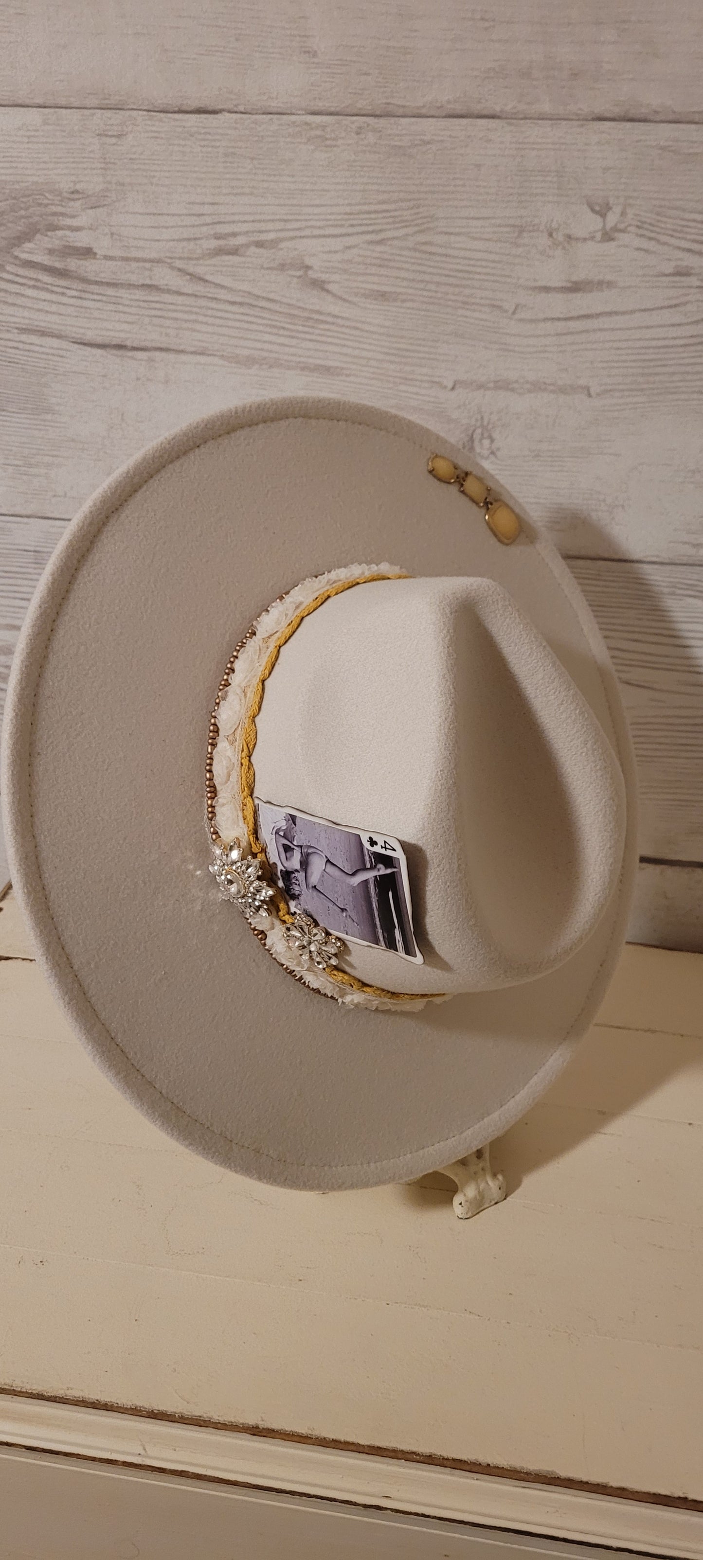Lace ribbon, sheer floral ribbon, golden seed beads, playing card & rhinestone brooches Felt hat Flat brim 65% polyester and 35% cotton Ribbon drawstring for hat size adjustment Head Circumference: 24" Crown Height: 5" Brim Length: 15.75" Brim Width: 14.5" Branded & numbered inside crown Custom designed by Kayla