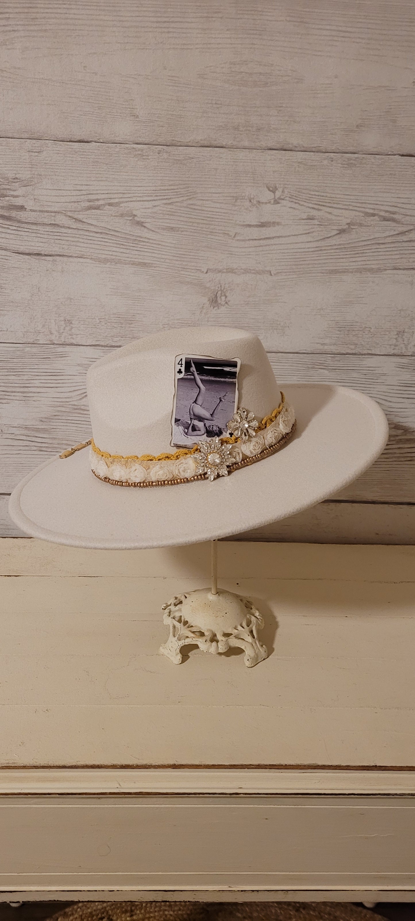 Lace ribbon, sheer floral ribbon, golden seed beads, playing card & rhinestone brooches Felt hat Flat brim 65% polyester and 35% cotton Ribbon drawstring for hat size adjustment Head Circumference: 24" Crown Height: 5" Brim Length: 15.75" Brim Width: 14.5" Branded & numbered inside crown Custom designed by Kayla