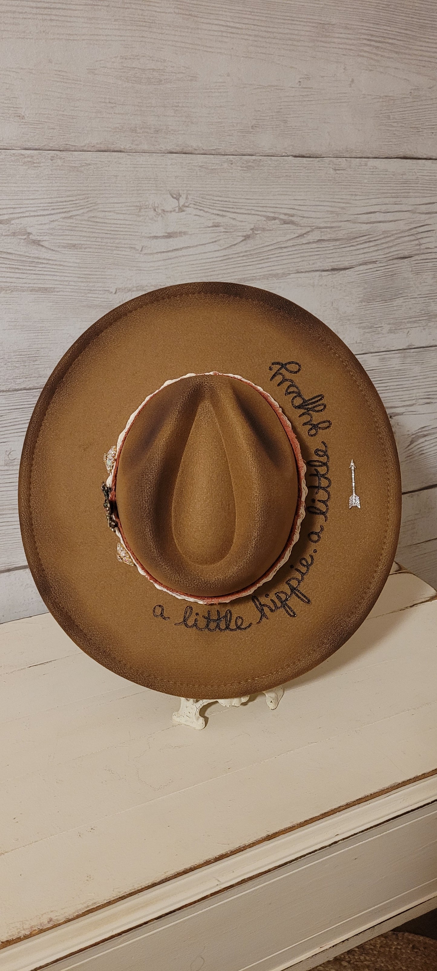 Features "a little hippie. a little gypsy." Natural lace ribbon, frayed velvet ribbon, rhinestone brooches: AB flowers, cactus & arrow Felt hat Flat brim 90% polyester & 10% PU Ribbon drawstring for hat size adjustment Head Circumference: 24" Crown Height: 5" Brim Length: 15.75" Brim Width: 14.5" Branded & numbered inside crown Custom burned & engraved by Kayla