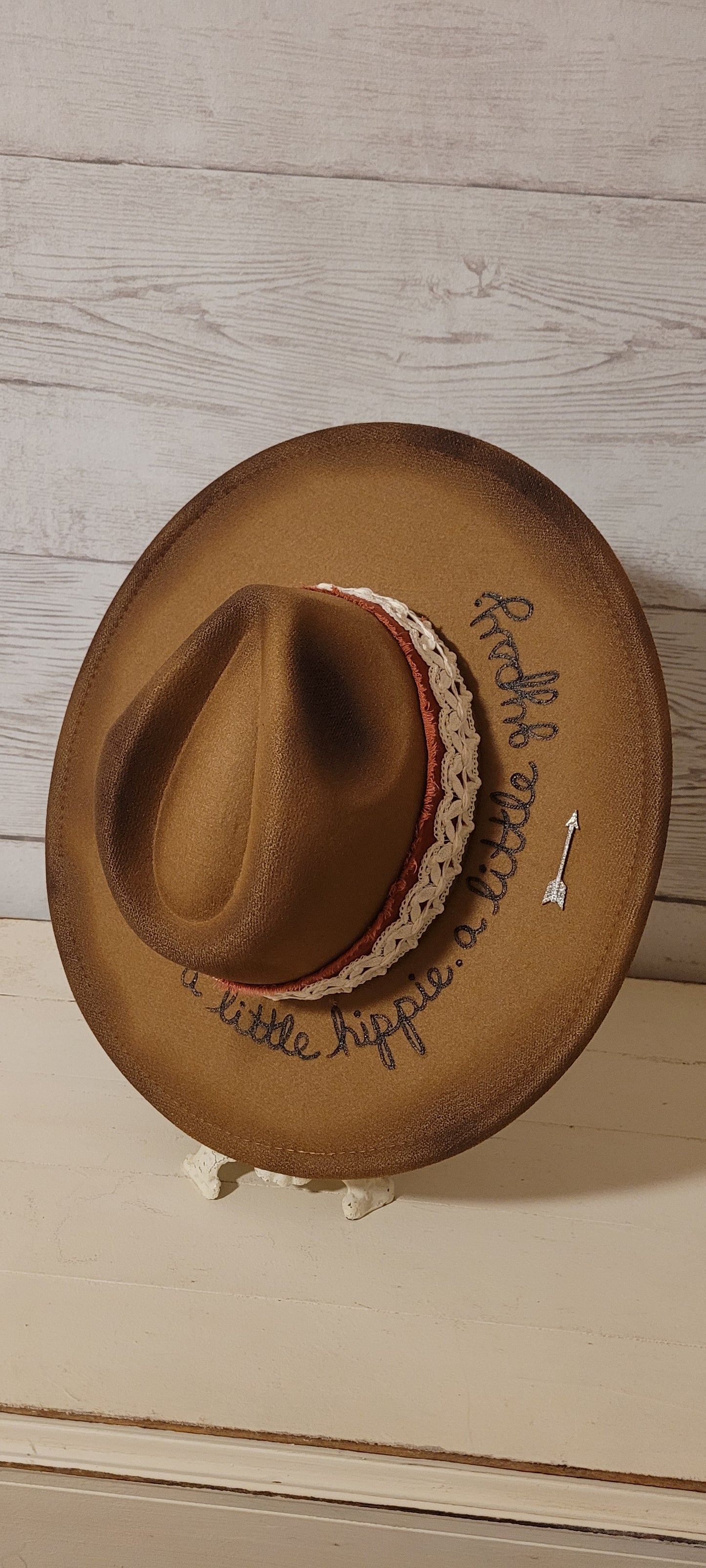 Features "a little hippie. a little gypsy." Natural lace ribbon, frayed velvet ribbon, rhinestone brooches: AB flowers, cactus & arrow Felt hat Flat brim 90% polyester & 10% PU Ribbon drawstring for hat size adjustment Head Circumference: 24" Crown Height: 5" Brim Length: 15.75" Brim Width: 14.5" Branded & numbered inside crown Custom burned & engraved by Kayla