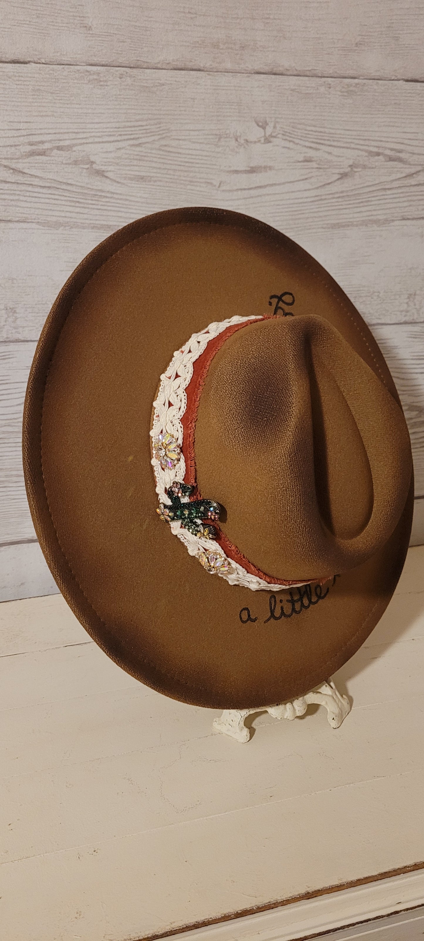 Features "a little hippie. a little gypsy." Natural lace ribbon, frayed velvet ribbon, rhinestone brooches: AB flowers, cactus & arrow Felt hat Flat brim 90% polyester & 10% PU Ribbon drawstring for hat size adjustment Head Circumference: 24" Crown Height: 5" Brim Length: 15.75" Brim Width: 14.5" Branded & numbered inside crown Custom burned & engraved by Kayla