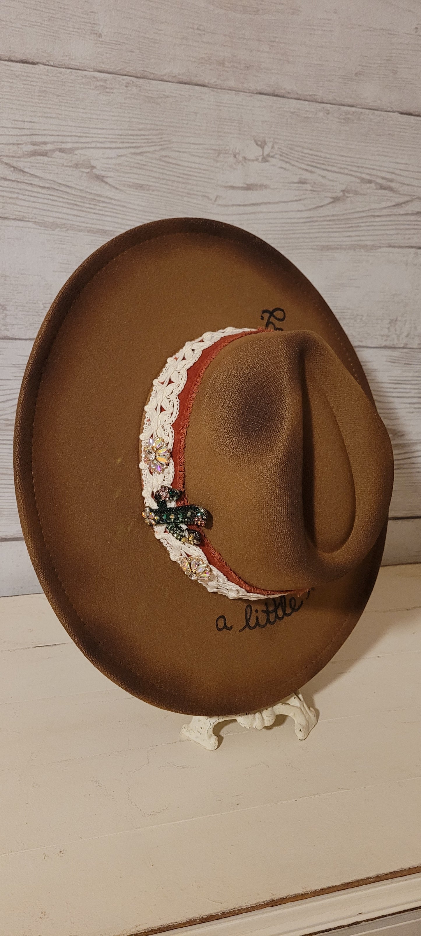 Features "a little hippie. a little gypsy." Natural lace ribbon, frayed velvet ribbon, rhinestone brooches: AB flowers, cactus & arrow Felt hat Flat brim 90% polyester & 10% PU Ribbon drawstring for hat size adjustment Head Circumference: 24" Crown Height: 5" Brim Length: 15.75" Brim Width: 14.5" Branded & numbered inside crown Custom burned & engraved by Kayla