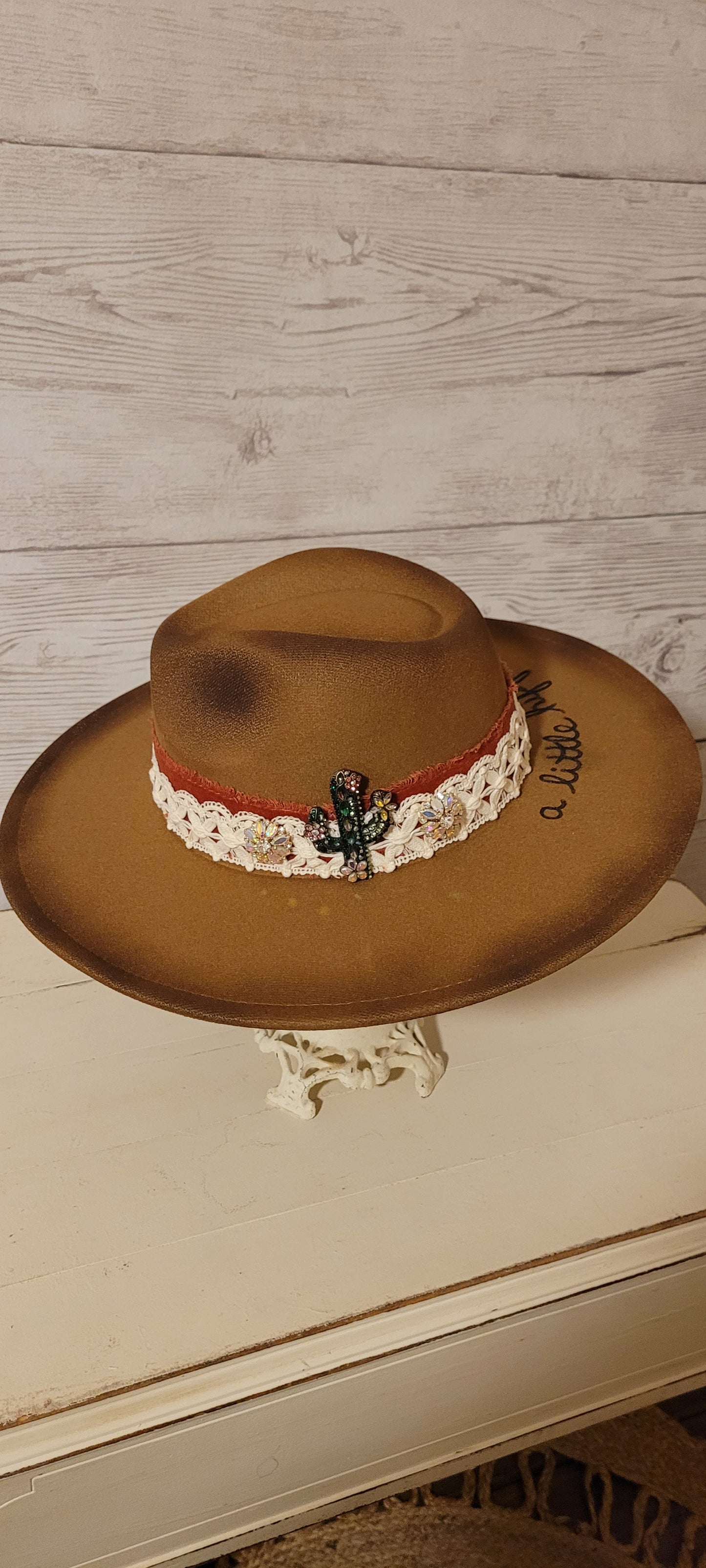 Features "a little hippie. a little gypsy." Natural lace ribbon, frayed velvet ribbon, rhinestone brooches: AB flowers, cactus & arrow Felt hat Flat brim 90% polyester & 10% PU Ribbon drawstring for hat size adjustment Head Circumference: 24" Crown Height: 5" Brim Length: 15.75" Brim Width: 14.5" Branded & numbered inside crown Custom burned & engraved by Kayla