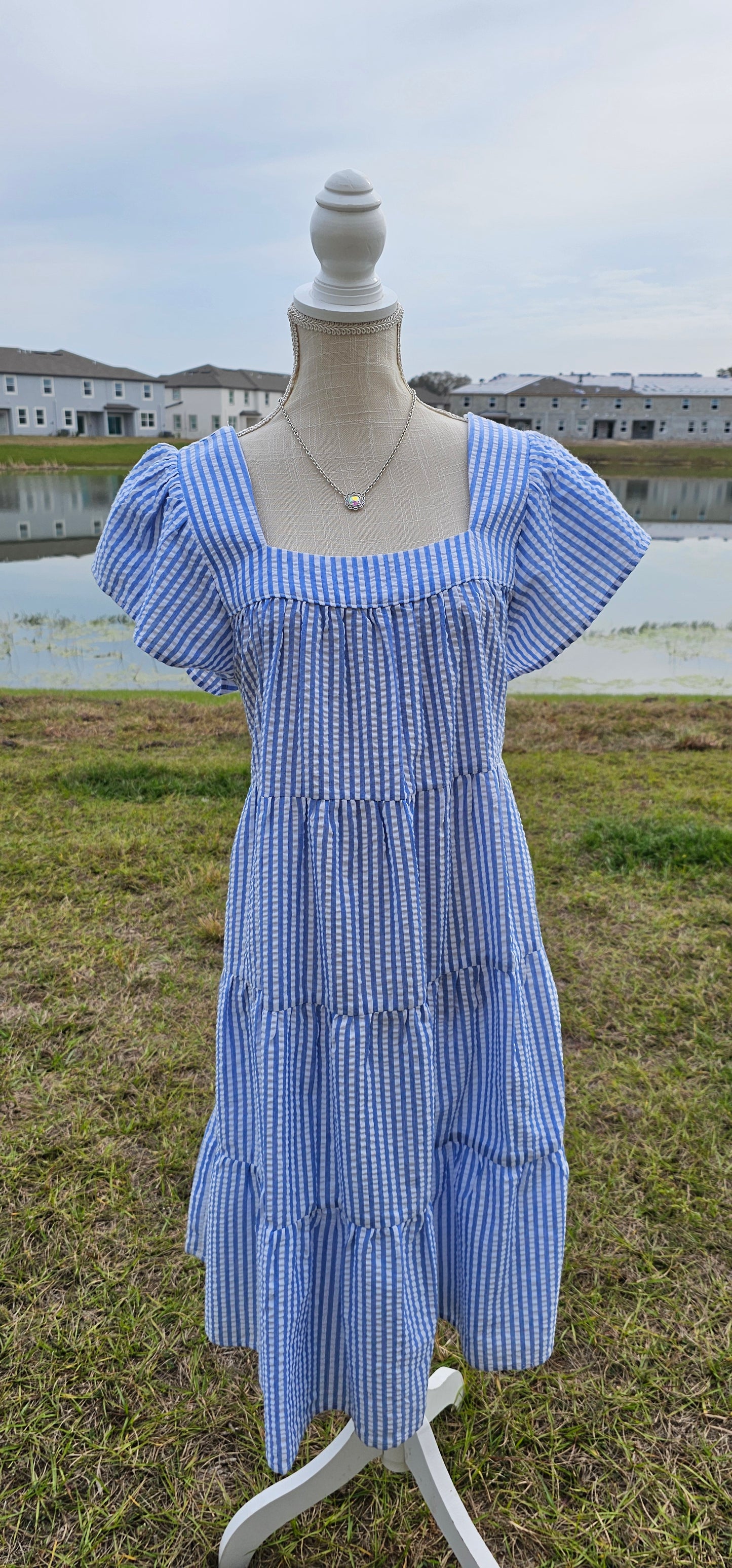 “Not In Kansas” dress features a square neckline and backline, ruffled sleeves, tiered and pleated layers, and a rounded hemline. This white and baby blue striped dress sits at the knees. This is a woven, seersucker fabric, breathable, non-stretch fabric, unlined, non-sheer, and lightweight. This dress is perfect for a beach getaway! Sizes small through large.
