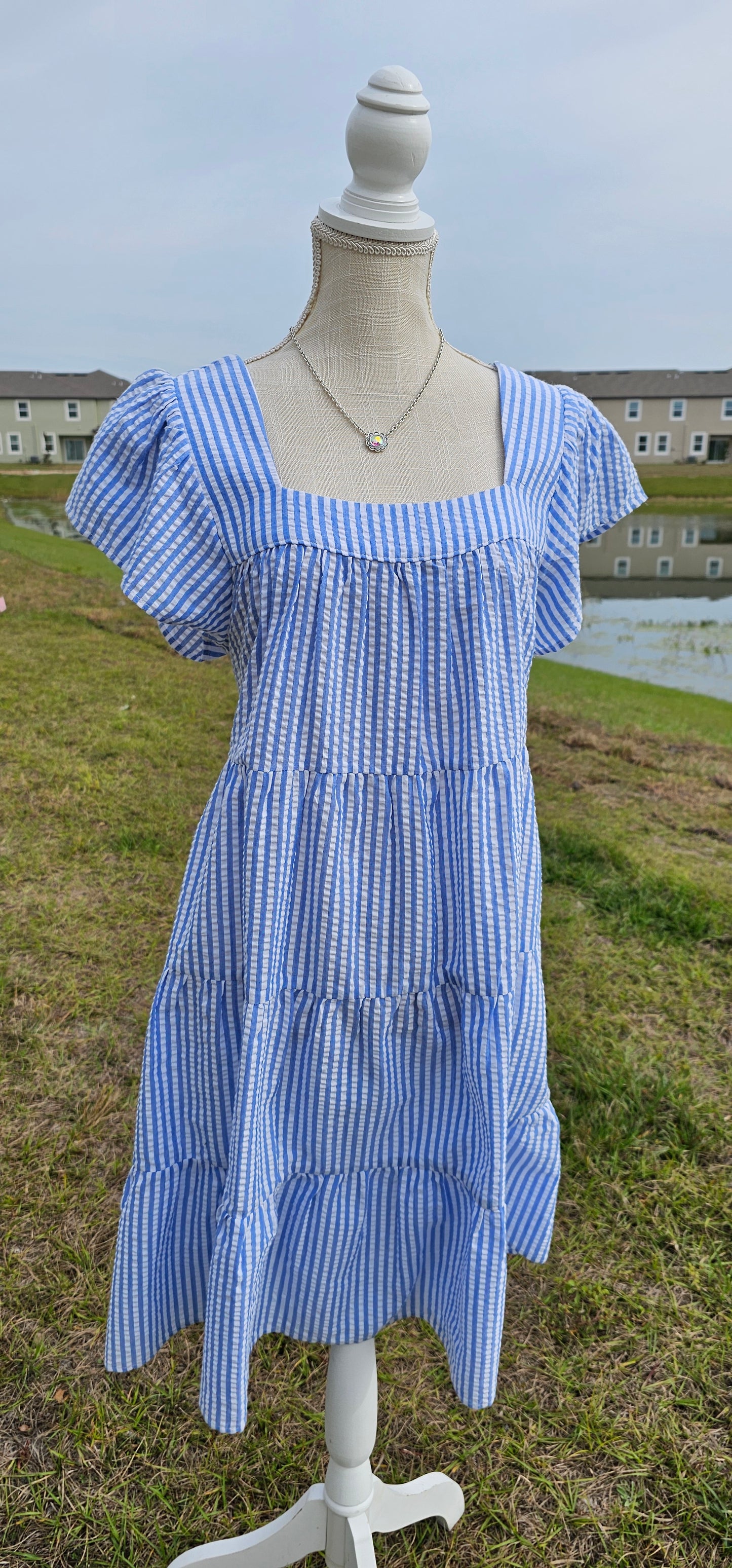 “Not In Kansas” dress features a square neckline and backline, ruffled sleeves, tiered and pleated layers, and a rounded hemline. This white and baby blue striped dress sits at the knees. This is a woven, seersucker fabric, breathable, non-stretch fabric, unlined, non-sheer, and lightweight. This dress is perfect for a beach getaway! Sizes small through large.