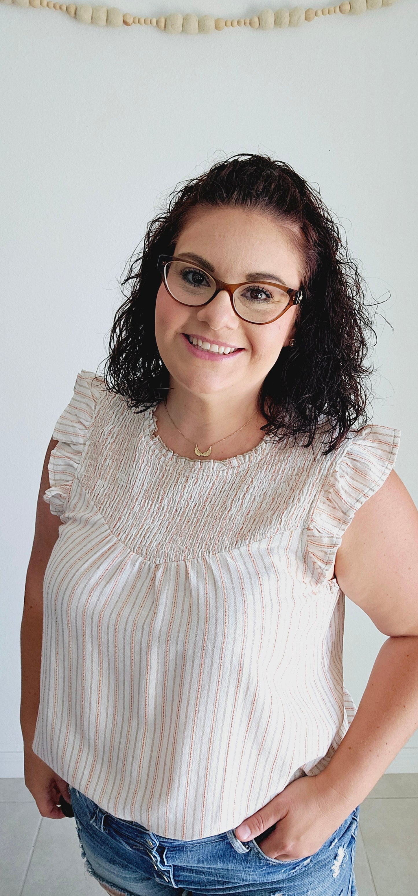 Add some fun to your wardrobe with this adorable blouse. Featuring a multi-color (taupe, mustard, red) stripe design, ruffle detail, and smocked chest, this sleeveless blouse is perfect for any occasion. Let your playful side shine through with this off white top! Sizes small through large.