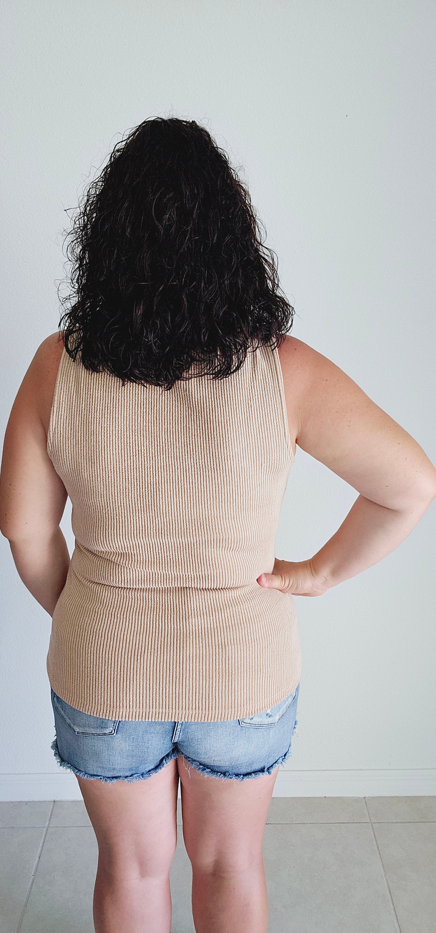 This tank top features a unique square neckline and a classic ribbed design in a washed tan color. Perfect for layering or wearing on its own, this tank is a versatile addition to your wardrobe. Sizes small through large.