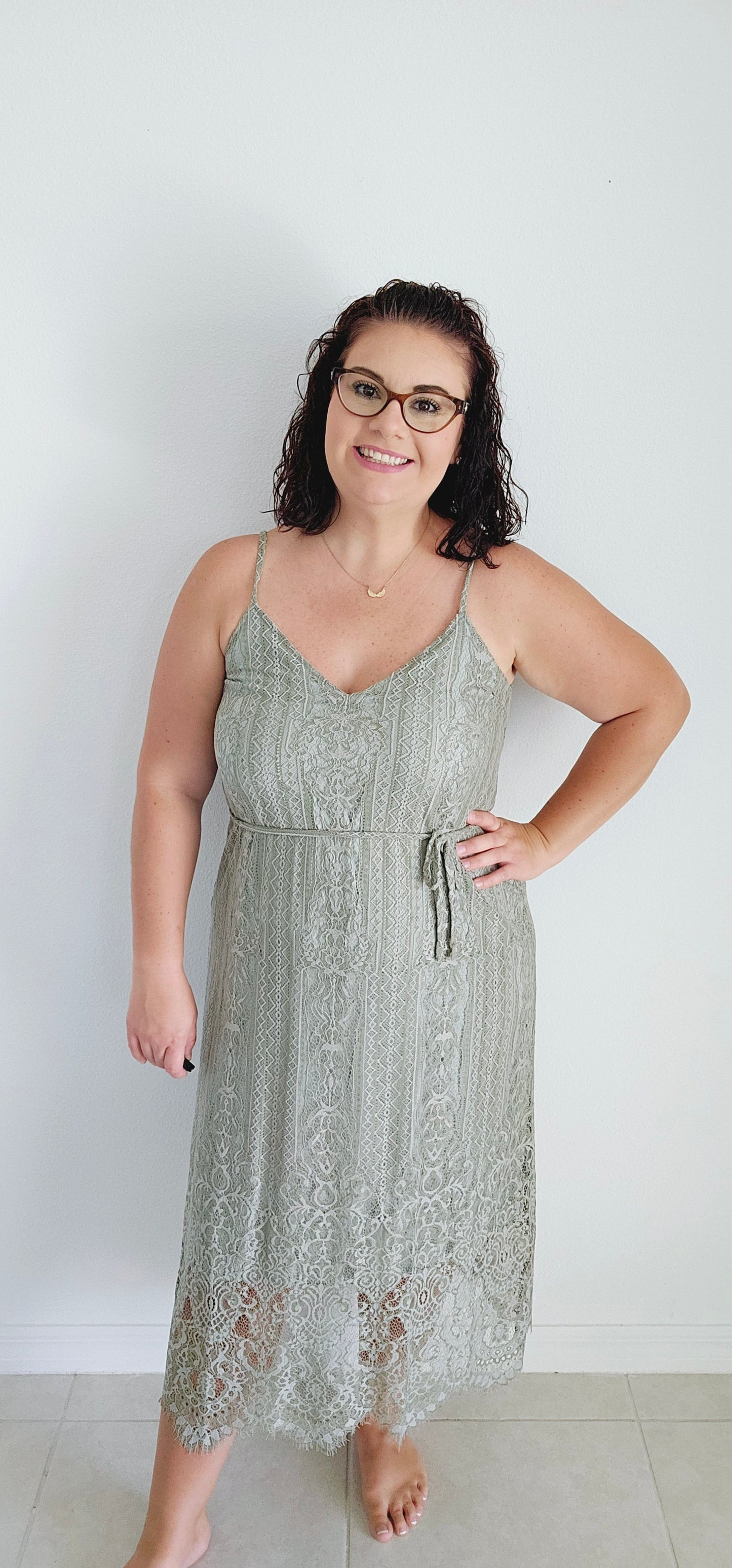 This A-line slip dress features a delicate lace overlay and a flattering waist tie, perfect for accentuating your figure. With adjustable shoulder straps and a soft rayon lining, this dress is both stylish and comfortable. Wear it to your next event for a touch of elegance with a modern twist. Sizes small through large.
