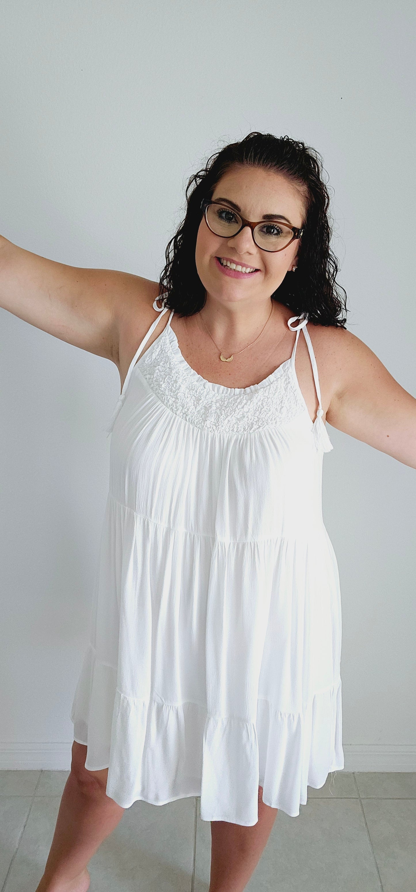 Get ready to make a statement with this flirty mini dress. Featuring a unique popcorn smocking chest and playful tassel detail straps, this dress is perfect for those vacation vibes. The tiered mini length adds a touch of fun and flirty to your look. Bring on the sun! Sizes small through large.