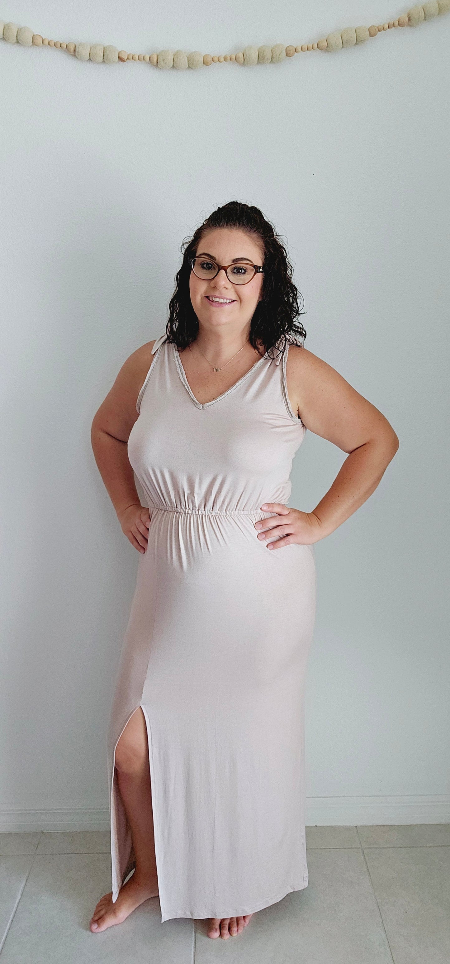 Shake up your wardrobe with this modern maxi dress. The v-neck and v-back add a playful touch to this elegant piece. The elastic waist ensures a comfortable fit while the tie detail and fabric trim add some fun texture. Sizes small through large.