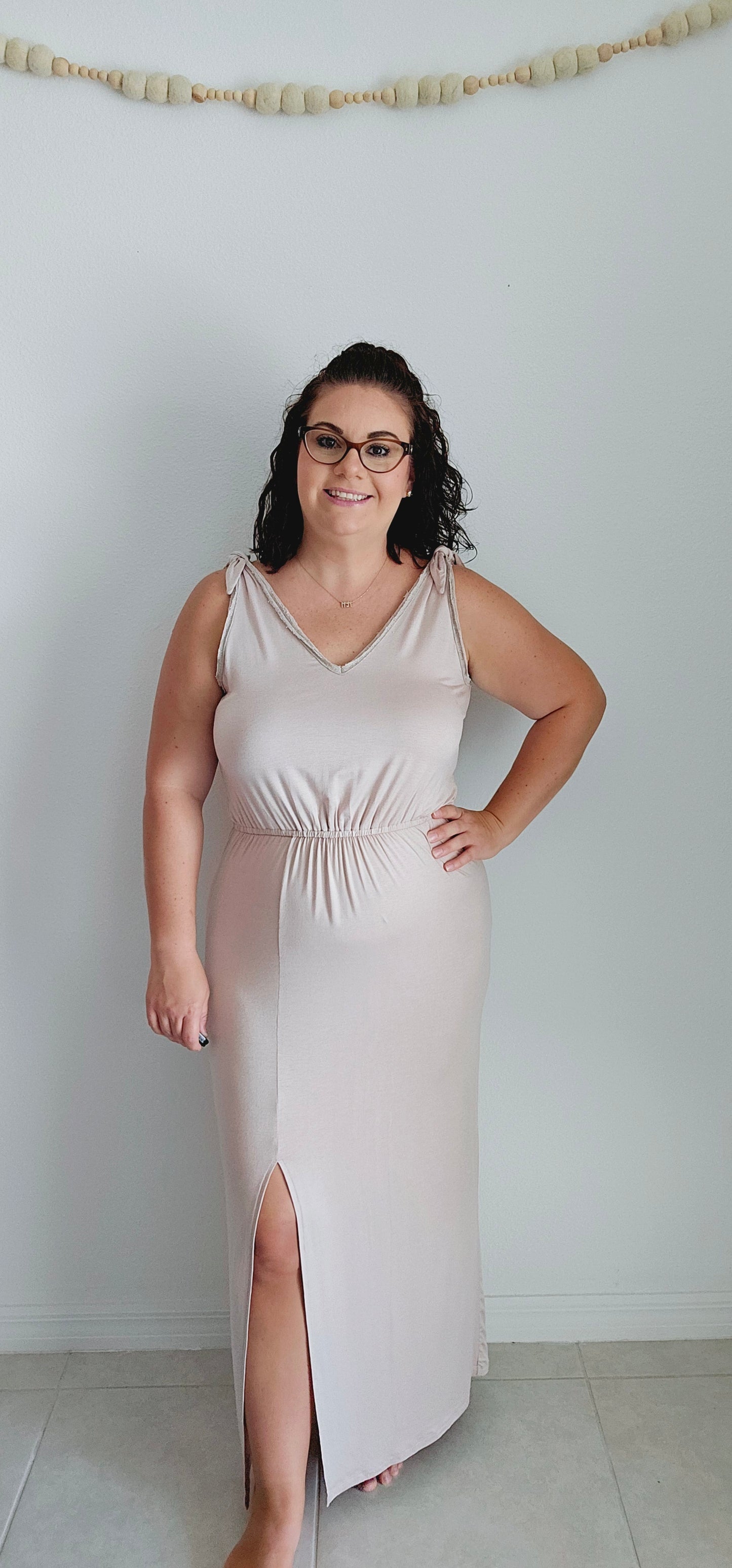 Shake up your wardrobe with this modern maxi dress. The v-neck and v-back add a playful touch to this elegant piece. The elastic waist ensures a comfortable fit while the tie detail and fabric trim add some fun texture. Sizes small through large.