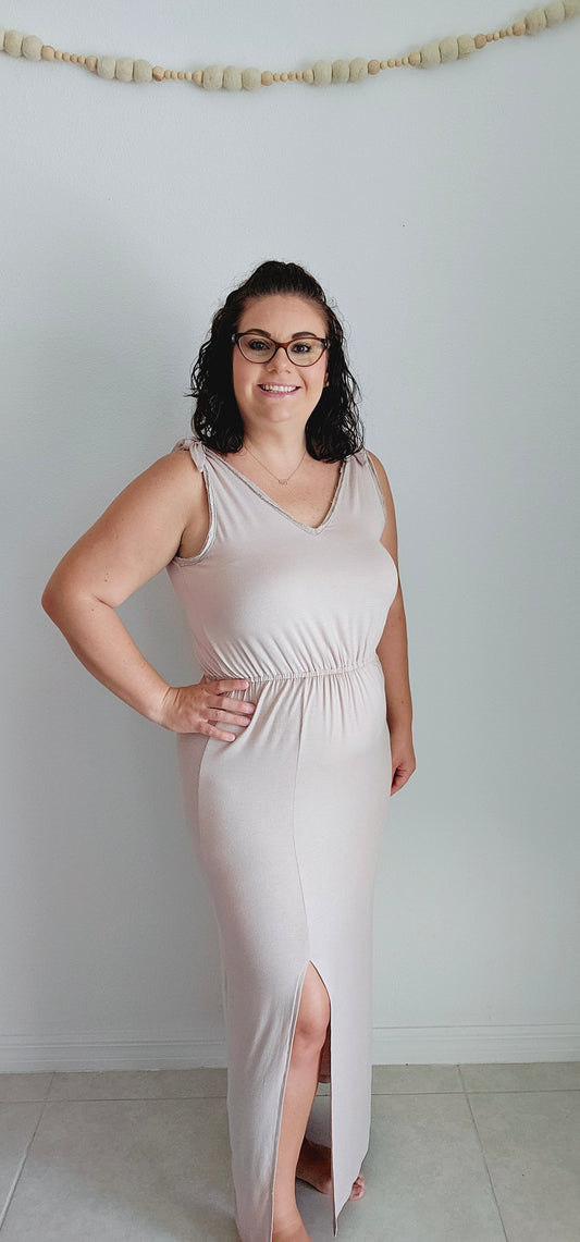 Shake up your wardrobe with this modern maxi dress. The v-neck and v-back add a playful touch to this elegant piece. The elastic waist ensures a comfortable fit while the tie detail and fabric trim add some fun texture. Sizes small through large.