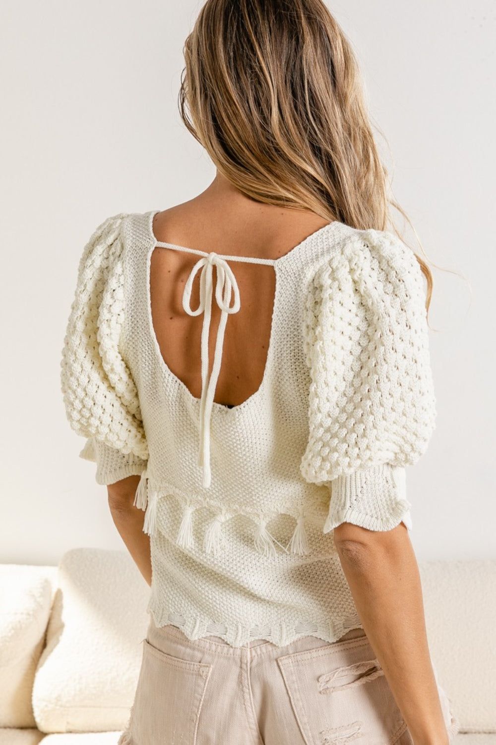 This short-sleeve tassel detail textured square neck sweater is a stylish and versatile piece for your wardrobe. The tassel detailing adds a playful and bohemian touch to the textured fabric. The square neck design offers a modern and flattering neckline. Pair it with high-waisted trousers for a chic office look, or with denim shorts for a casual weekend outfit. S-XL