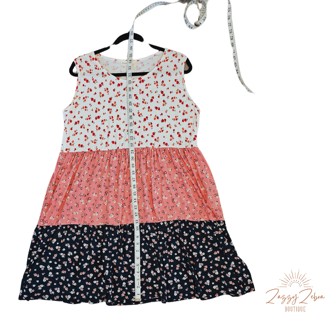 The “Flower Child“ dress is sleeveless, it features a rounded neckline, tiered layers, two functional pockets, and it sits above the knees. It is a buttery soft material. This is unlined, non-sheer, and lightweight. This dress is off white, dusty mauve, and navy blue with red, pink, and dusty mauve flowers. Sizes small through x-large.
