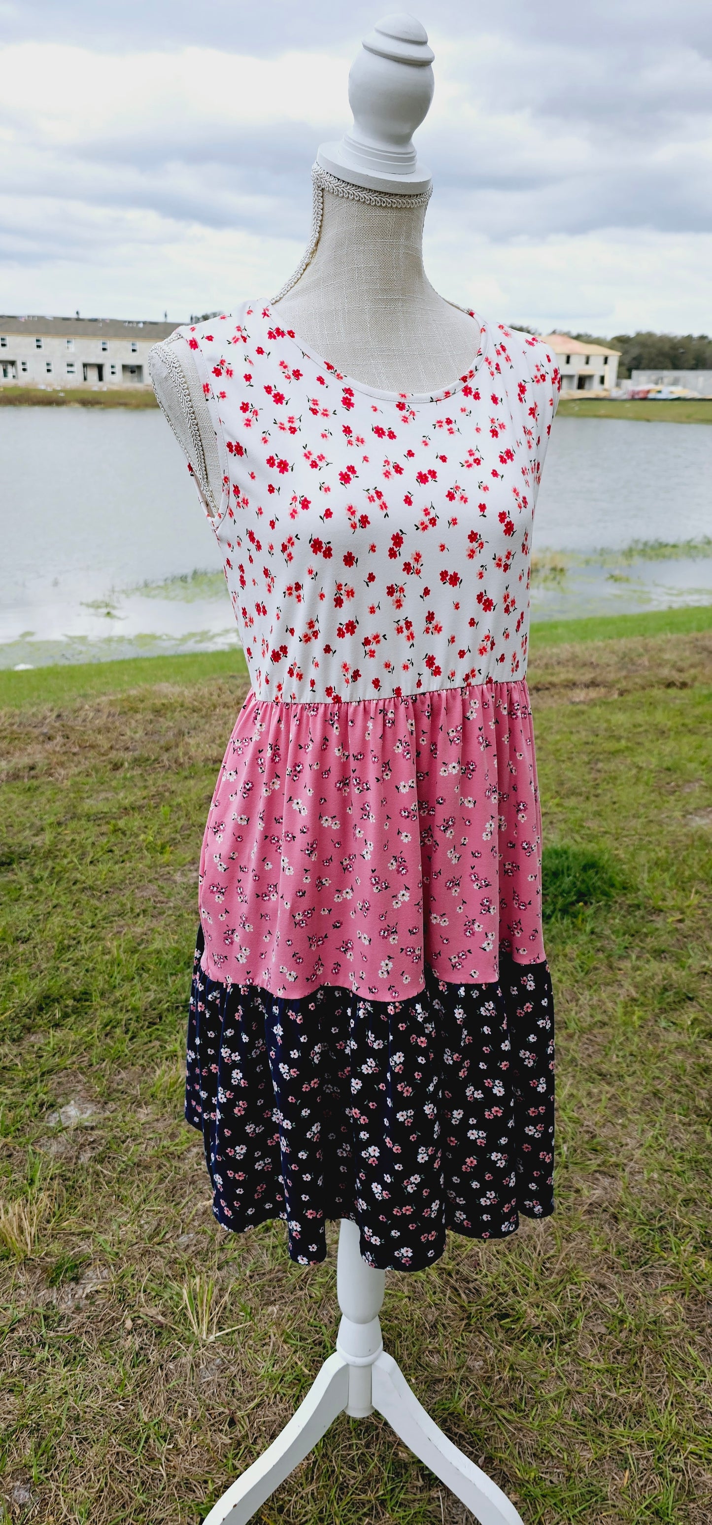 The “Flower Child“ dress is sleeveless, it features a rounded neckline, tiered layers, two functional pockets, and it sits above the knees. It is a buttery soft material. This is unlined, non-sheer, and lightweight. This dress is off white, dusty mauve, and navy blue with red, pink, and dusty mauve flowers. Sizes small through x-large.
