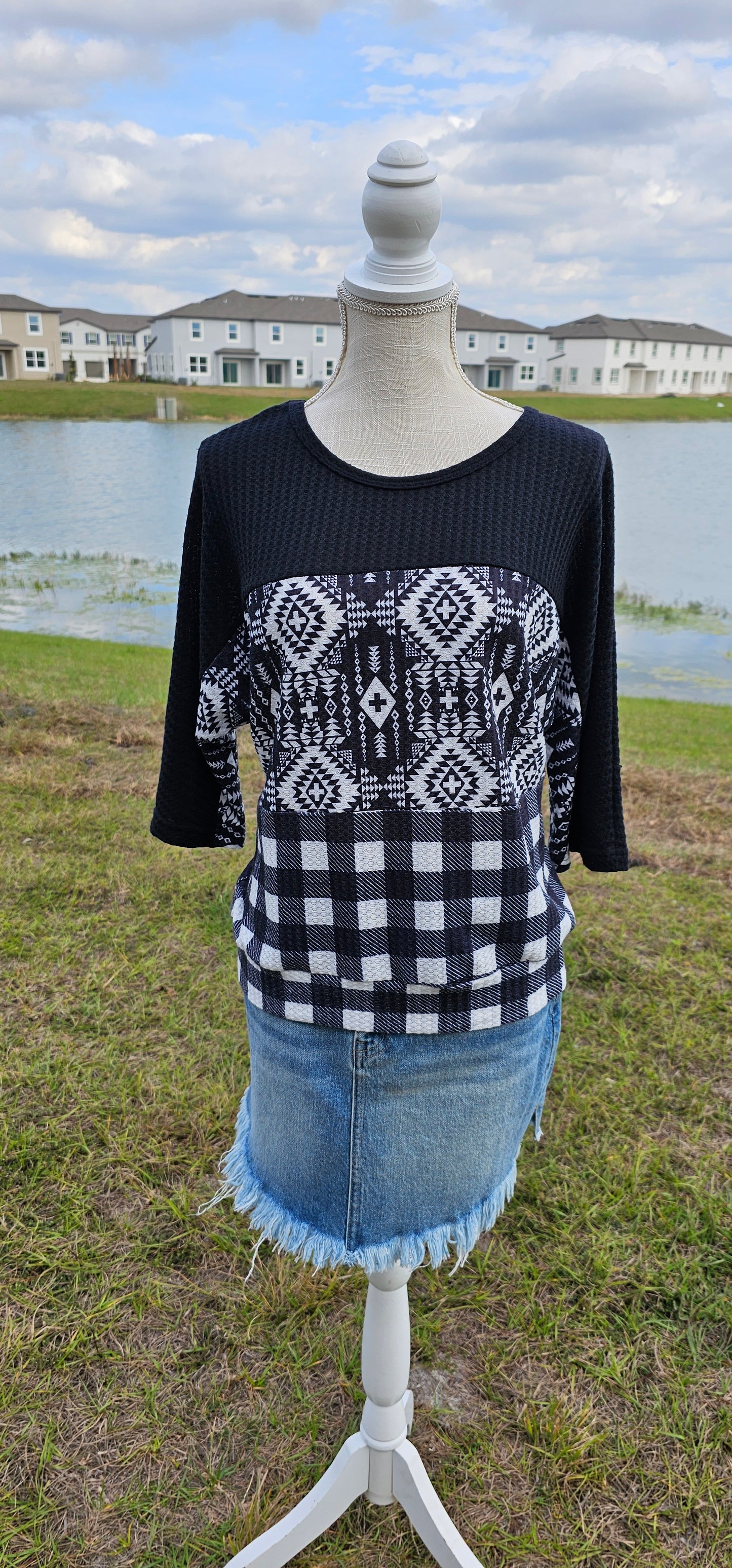 Imagine yourself in this super cute Buffalo Babe top. This is a waffle top that features a solid black block, an Aztec block print, and a buffalo checked block on the front and back. Buffalo Babe features a 3/4 sleeve which is solid black with loose fitting hem line. Go for comfort! Sizes small through x-large.
