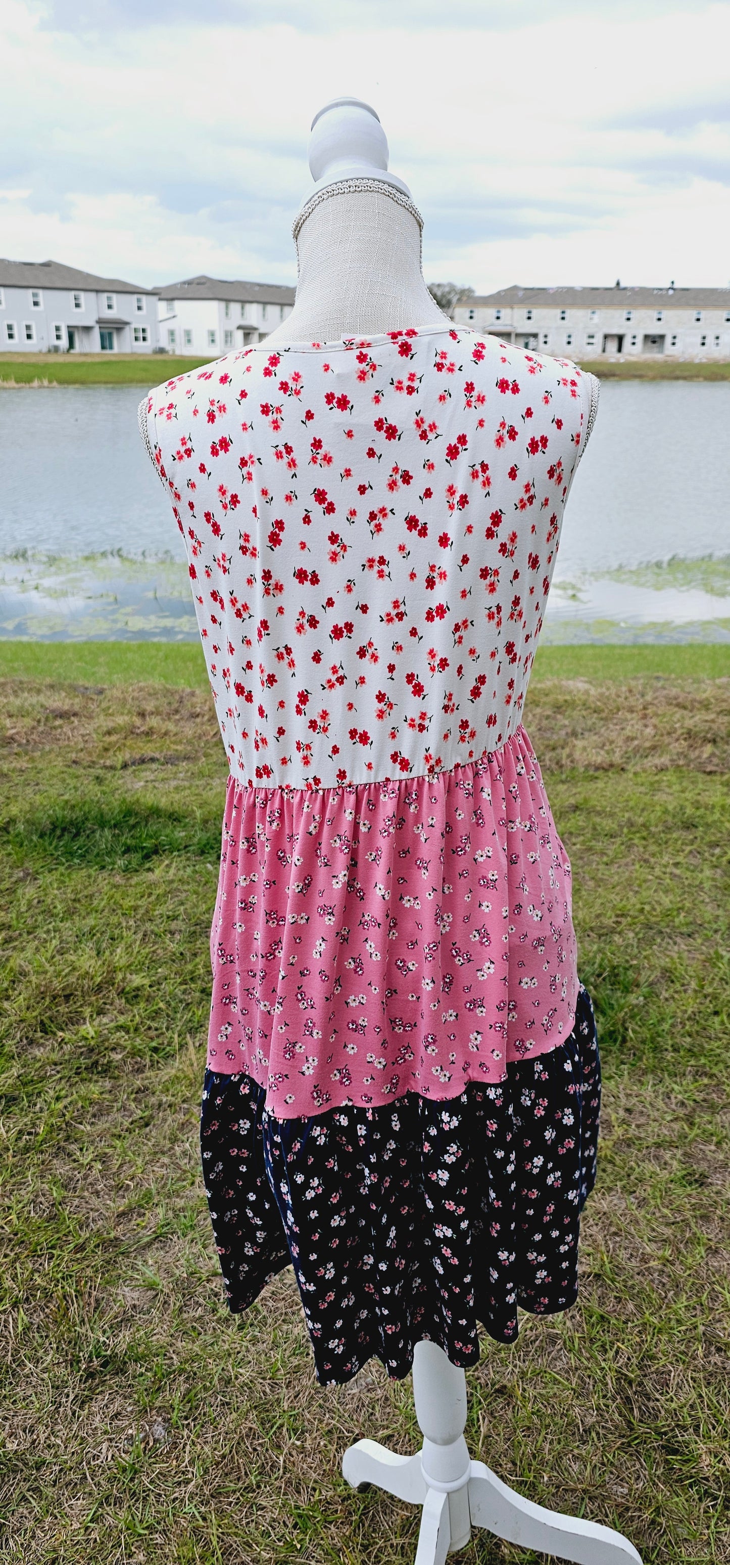 The “Flower Child“ dress is sleeveless, it features a rounded neckline, tiered layers, two functional pockets, and it sits above the knees. It is a buttery soft material. This is unlined, non-sheer, and lightweight. This dress is off white, dusty mauve, and navy blue with red, pink, and dusty mauve flowers. Sizes small through x-large.