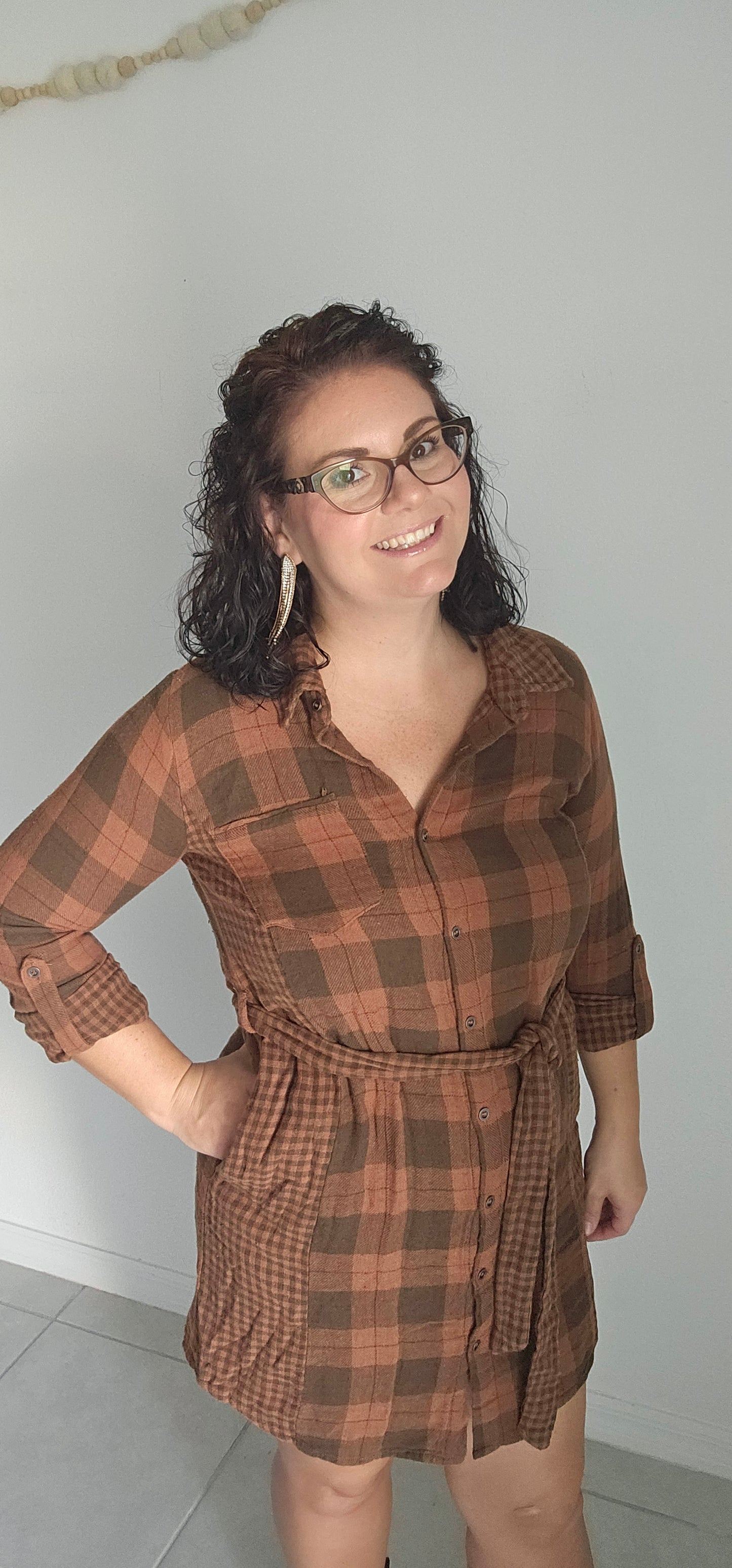 Step into autumn in style with the Riley Rust Plaid Shirt Dress! This warm plaid dress has all the details that make it a stand-out: buttoned front, tie-waist belt, plus functional chest and side pockets. Roll up the sleeves and get ready to kick up some fallen leaves. It's sure to get you noticed! Sizes small through large.