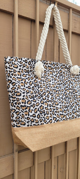 This leopard print tote features a cream color braided handle with a zipper top.  The material is polyester. The inside has a lining with a pocket for all of the small stuff that you do not want to get lost.  The outside bottom has a burlap color fabric. This tote is very versatile.  Imagine yourself heading to the beach, going shopping, or heading to the local market, you will get a lot of use out of this super cute tote.