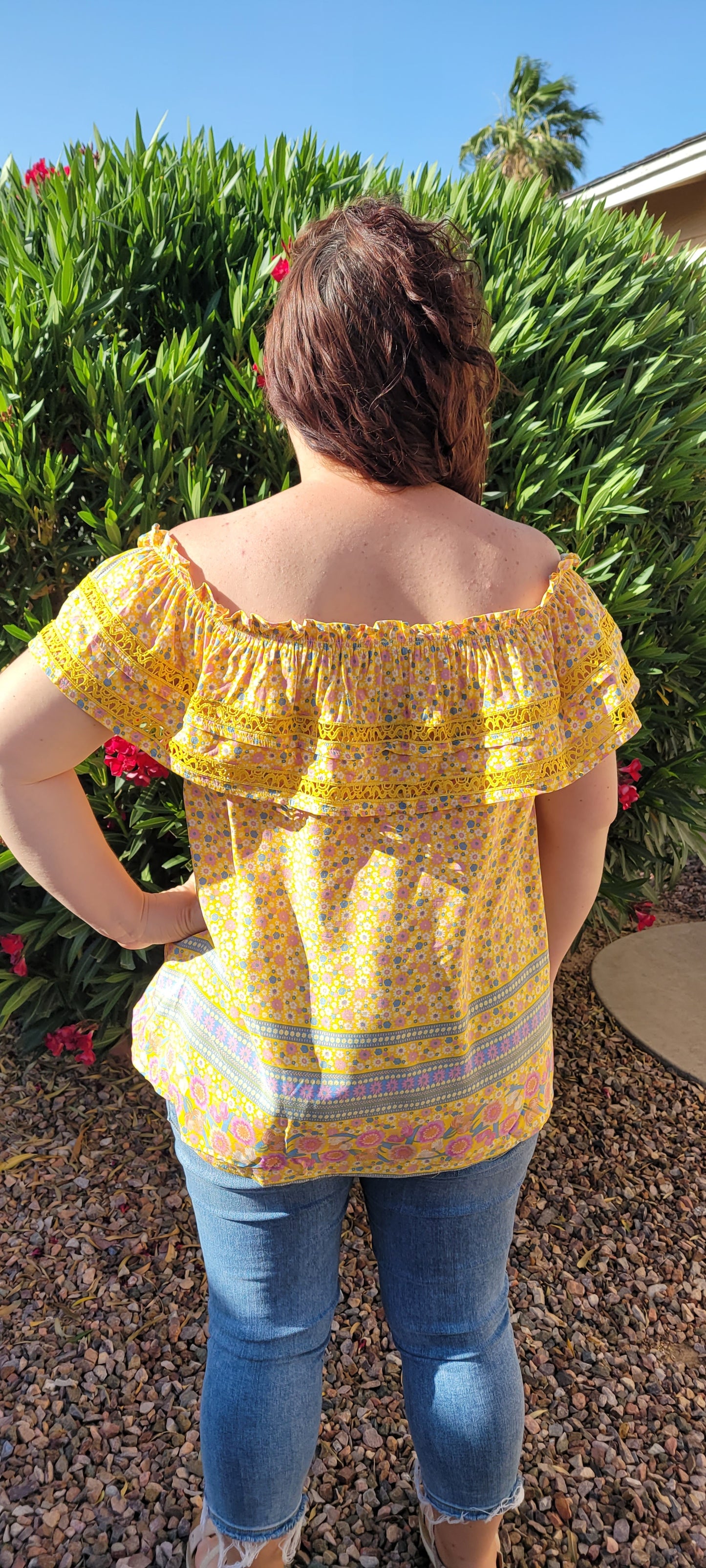 “Sunshine On My Shoulders” is an off the shoulder smock top. This top features a ray of subdued colors (dandelion yellow, mauve, ceil blue, white), elastic ruffled neckline, and crochet lace design. This top is a longer length, it does not have stretch, and is super lightweight and breathable. Sizes small through large.