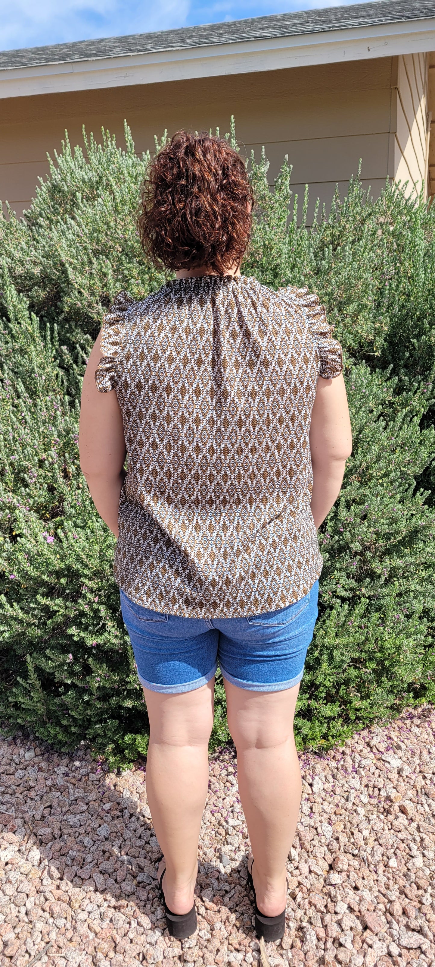 “Pretty Penny” is a patterned sleeveless blouse featuring a rounded hemline, a ruffled elastic neckline and ruffled sleeves. It is a waffle knit, relaxed fit. This is unlined, non-sheer, and lightweight. The colors are camel, white and black. Sizes small, medium and large