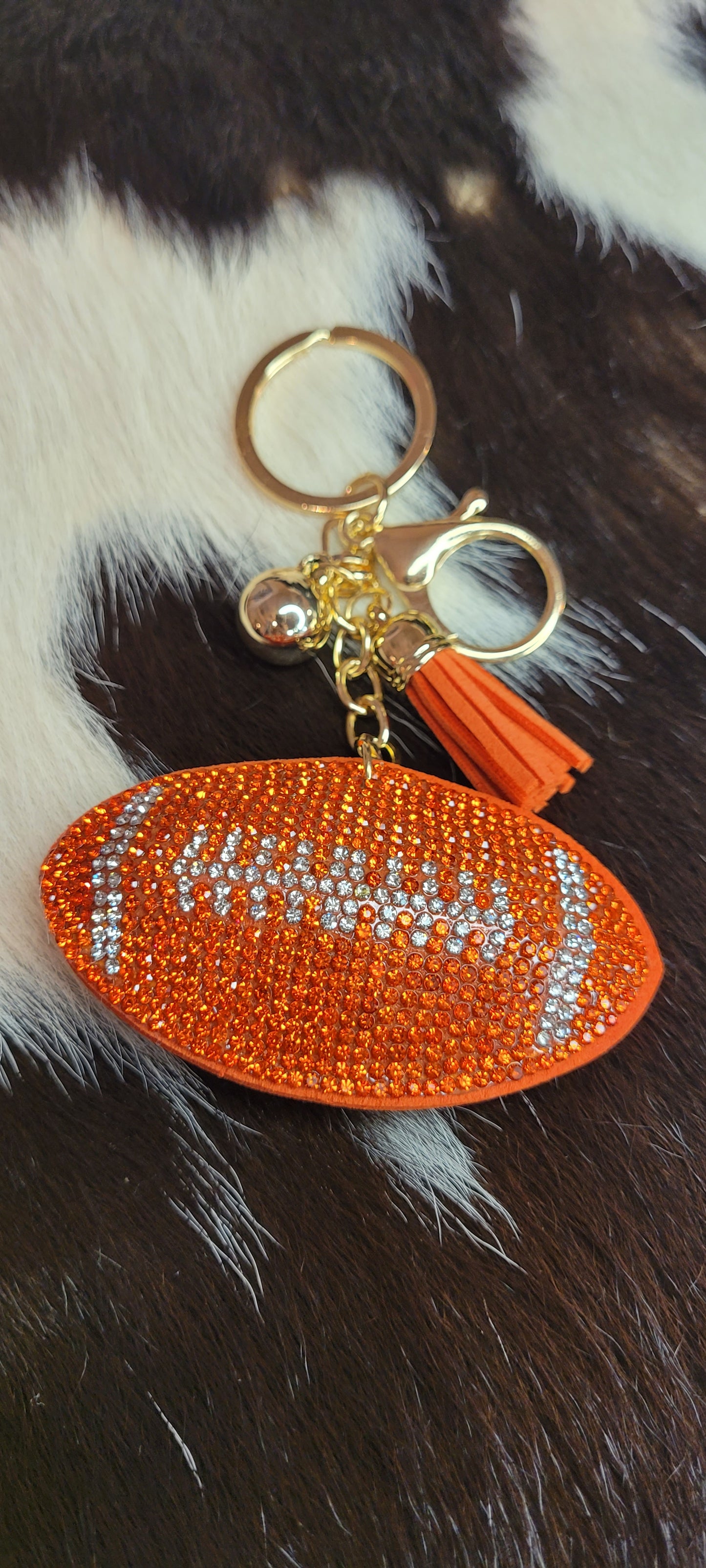 Football keychain Rhinestones are orange and clear in the shape of a football Faux leather backing and tassel Gold color chain, key ring and ball These key chains will not last long