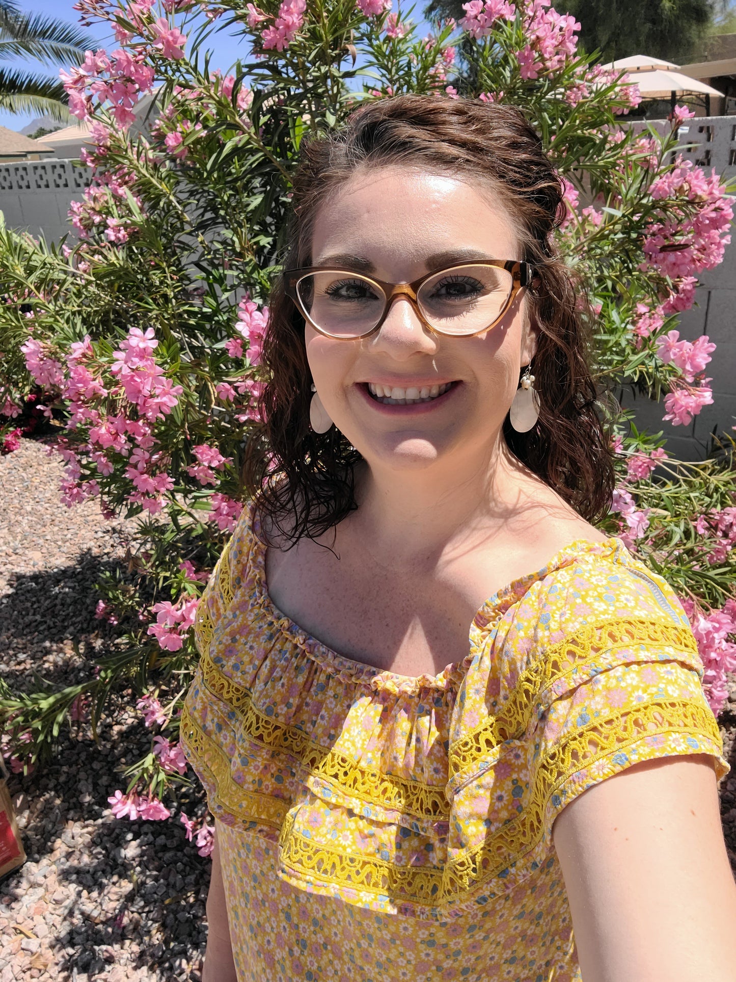 “Sunshine On My Shoulders” is an off the shoulder smock top. This top features a ray of subdued colors (dandelion yellow, mauve, ceil blue, white), elastic ruffled neckline, and crochet lace design. This top is a longer length, it does not have stretch, and is super lightweight and breathable. Sizes small through large.