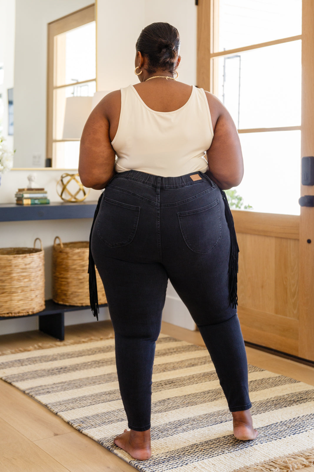 If there's anyone who can totally rock the Hilary Side Fringe Skinny Jegging In Black it's you! These western inspired jeggings feature a mid-rise waist with faux front pockets topping a skinny pant leg. Faux suede fringe decorates either side of these jeans adding a unique and stylish touch. Add cowboy boots and a crop top for a super fun look! 0 - 24W