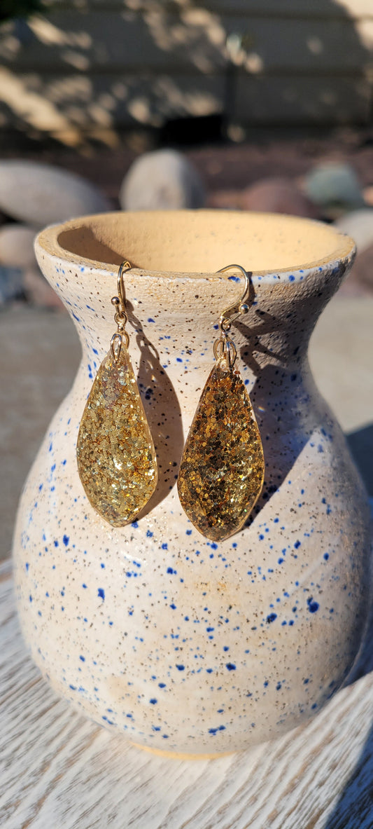 Genie bottle shape Gold glitter Epoxy material Light weight Brushed gold fish hook dangle earrings Rubber earring back Length 1.75”, width 0.75” Whether you want to be on the wild side or classy this earring set it will add a fun touch to your outfit