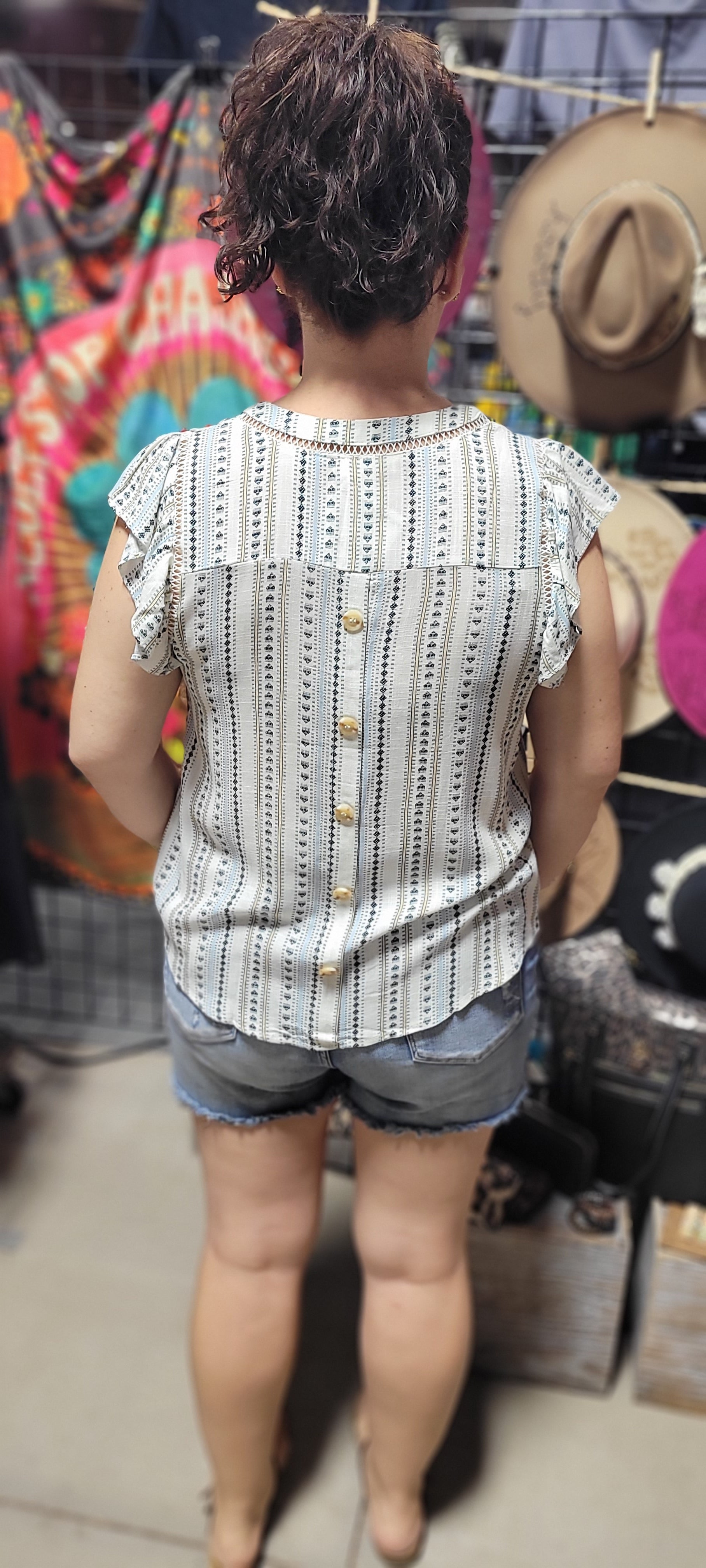 Be cool and breezy with this chambray-inspired Cindy Ivory &amp; Blue Patterned Top! Its v-neckline and short ruffle sleeves with lace trim give it a sweet and sassy look. The back yoke and non-functional buttons round out the look, with a subtle hint of western-style flair. Yee-haw!! Sizes small through large.