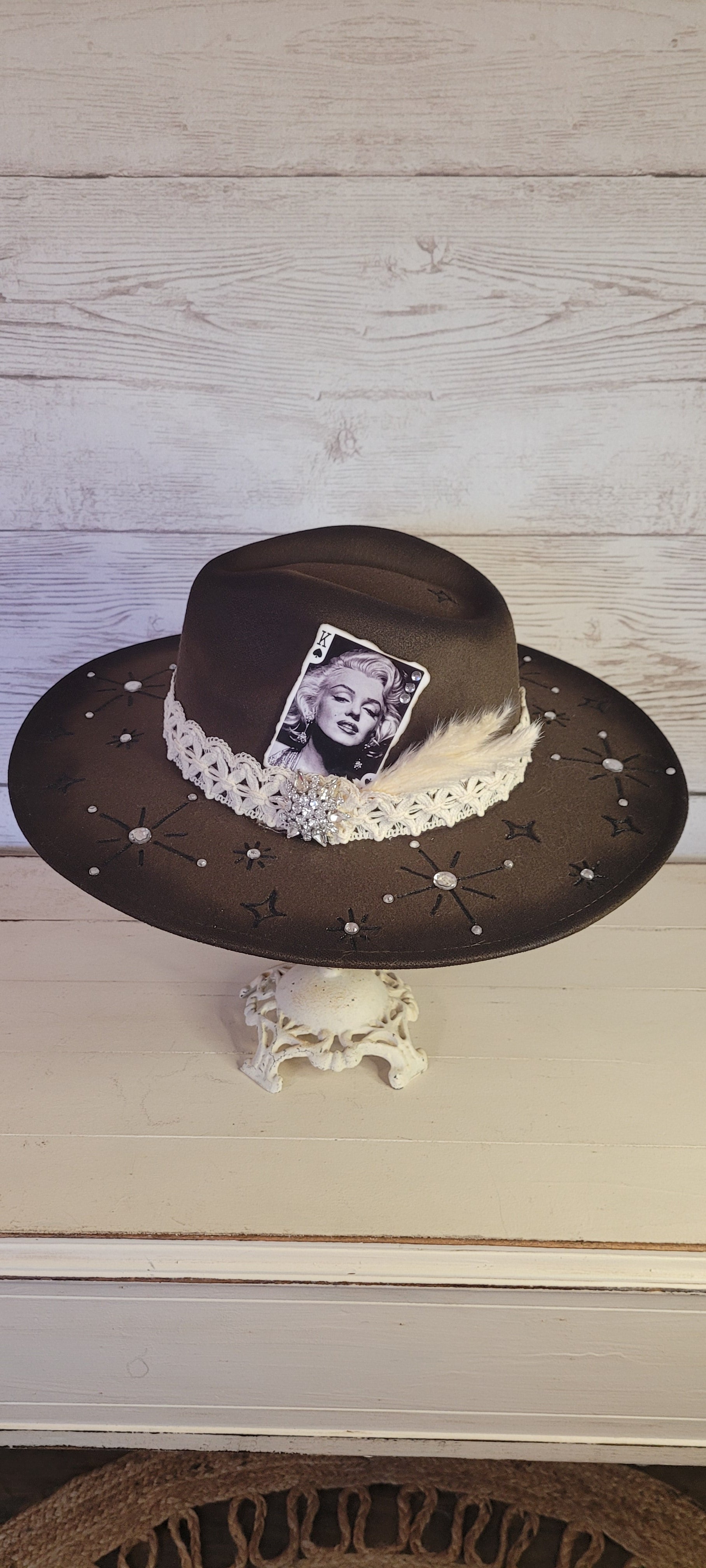 Features engraved stars & diamonds Rhinestone details throughout, pampas, crystal brooch, & playing card Felt hat Flat brim 65% polyester and 35% cotton Ribbon drawstring for hat size adjustment Head Circumference: 24" Crown Height: 5" Brim Length: 15.75" Brim Width: 14.5" Branded & numbered inside crown Custom designed by Kayla