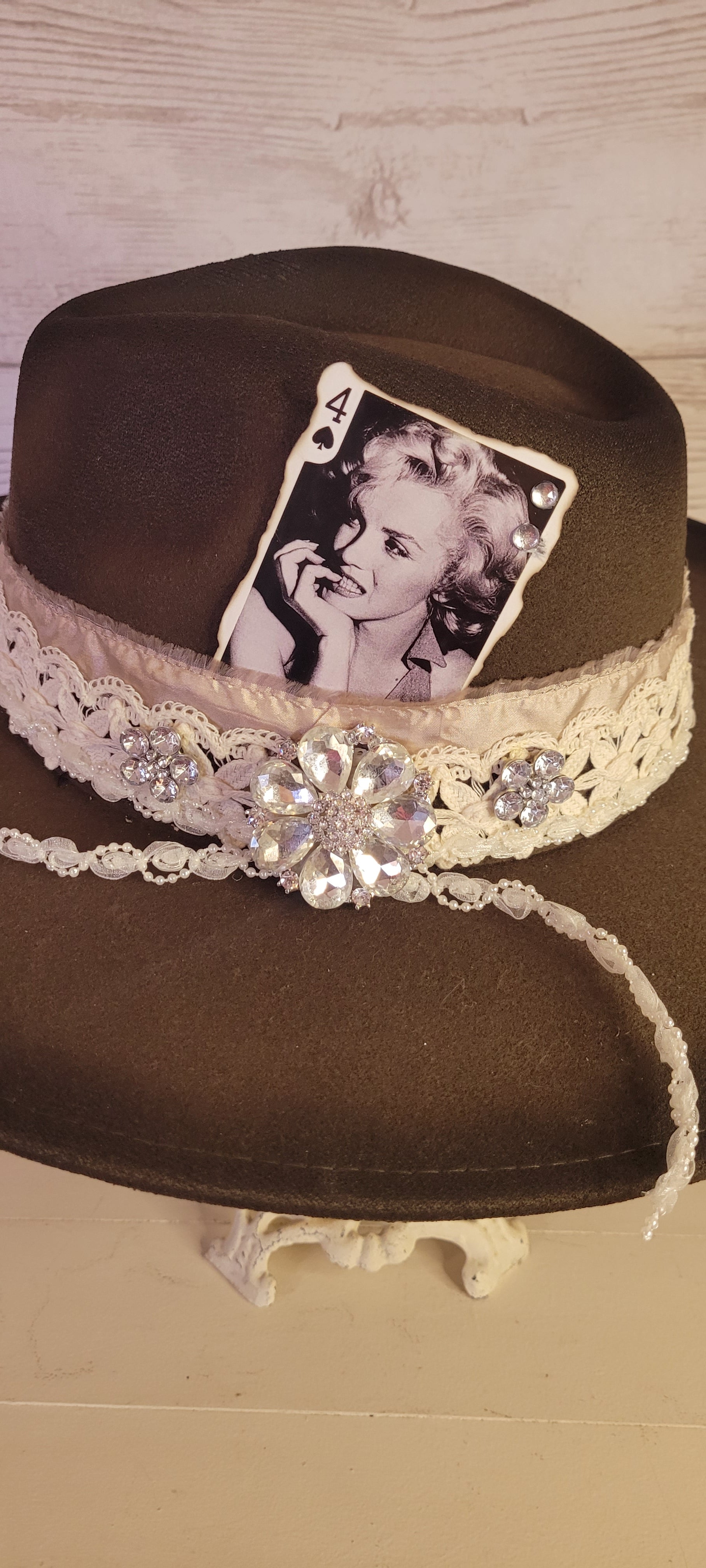Features rhinestone details on brim, crystal brooches, & playing card, light rose ribbon, natural lace ribbon, pearl ribbon Felt hat Flat brim 65% polyester and 35% cotton Ribbon drawstring for hat size adjustment Head Circumference: 24" Crown Height: 5" Brim Length: 15.75" Brim Width: 14.5" Branded & numbered inside crown Custom designed by Kayla