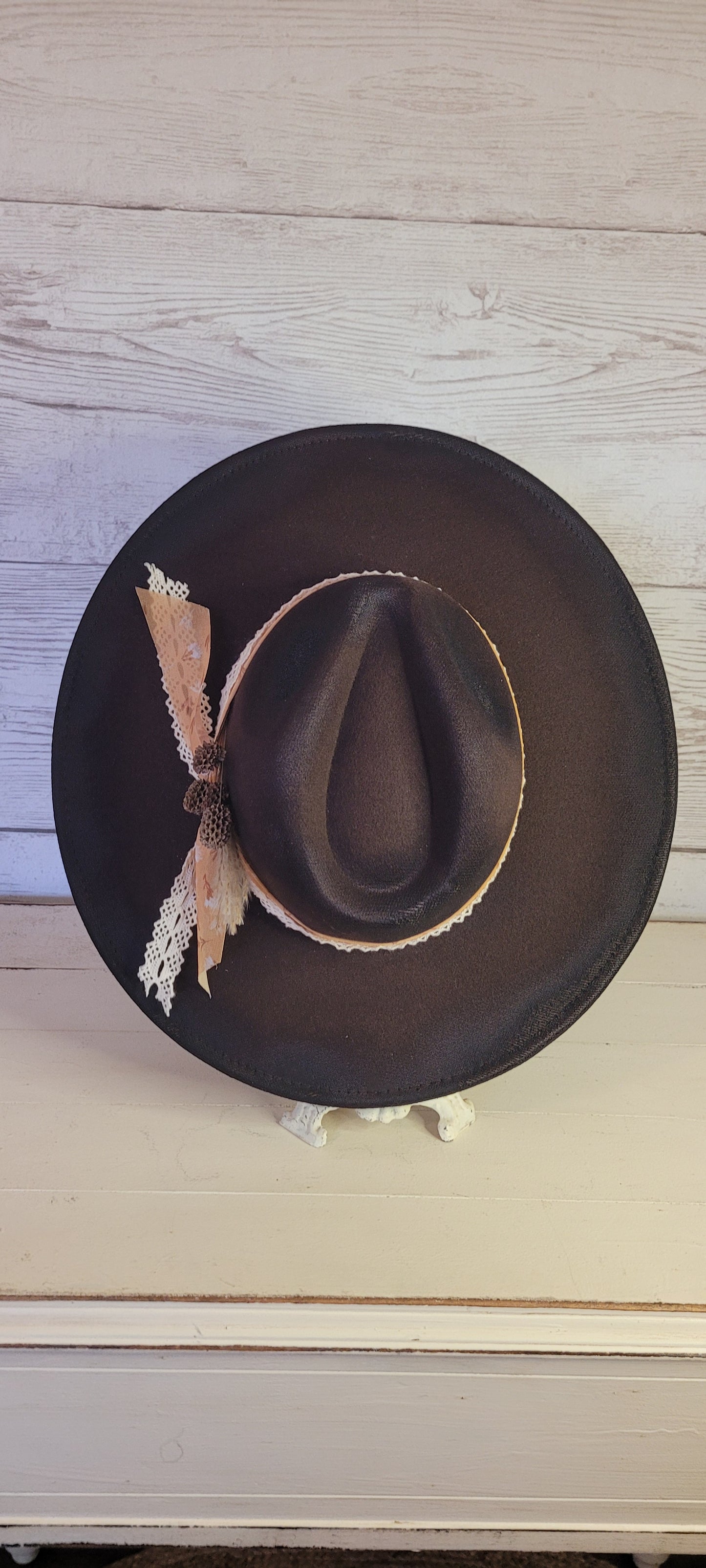 Features natural lace ribbon, sheer mustard ribbon, pine cones, & pampas Felt hat Flat brim 65% polyester and 35% cotton Ribbon drawstring for hat size adjustment Head Circumference: 24" Crown Height: 5" Brim Length: 15.75" Brim Width: 14.5" Branded & numbered inside crown Custom designed by Kayla