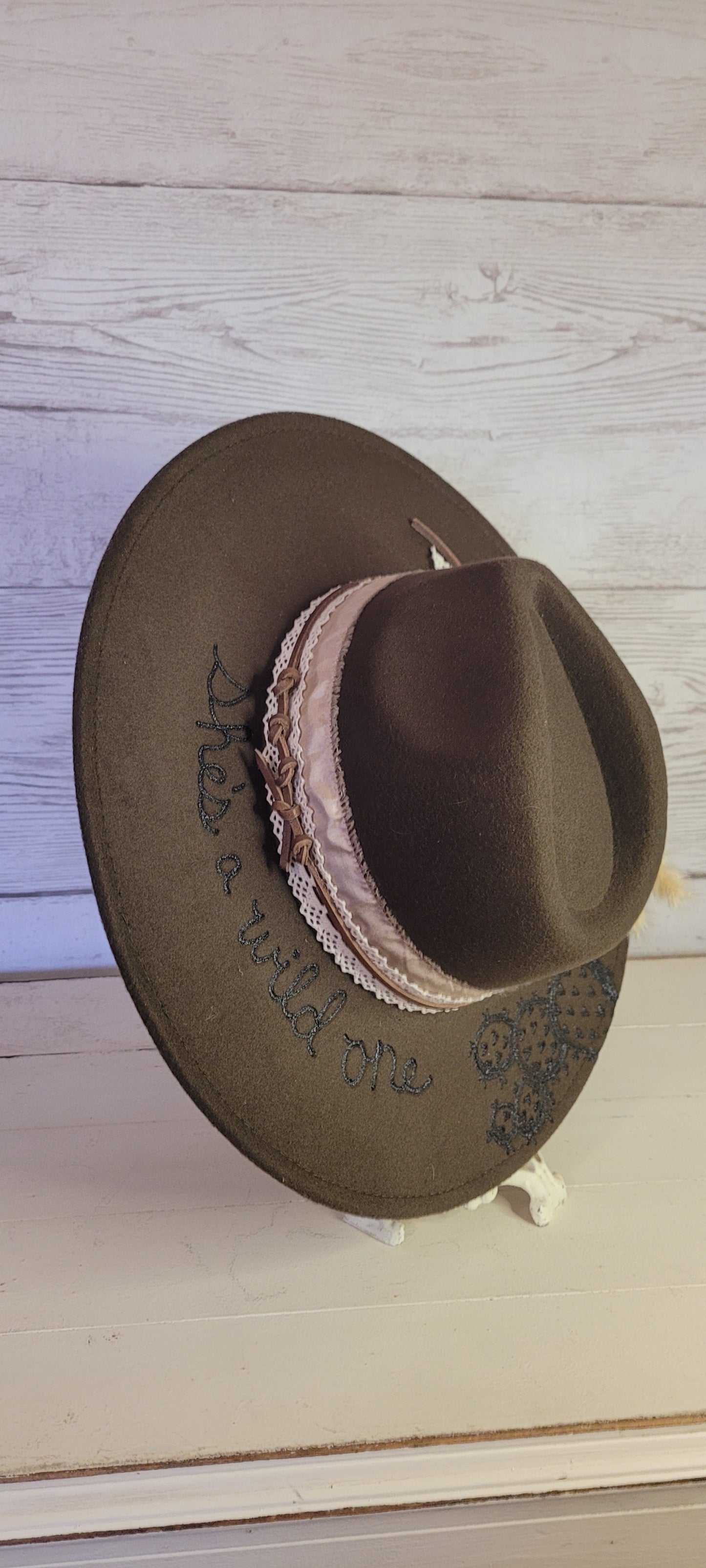Features "She's a wild one" & cactus engraving Pampas, pine cones, light rose ribbon, natural lace ribbon, leather band Felt hat Flat brim 65% polyester and 35% cotton Ribbon drawstring for hat size adjustment Head Circumference: 24" Crown Height: 5" Brim Length: 15.75" Brim Width: 14.5" Branded & numbered inside crown Custom designed by Kayla
