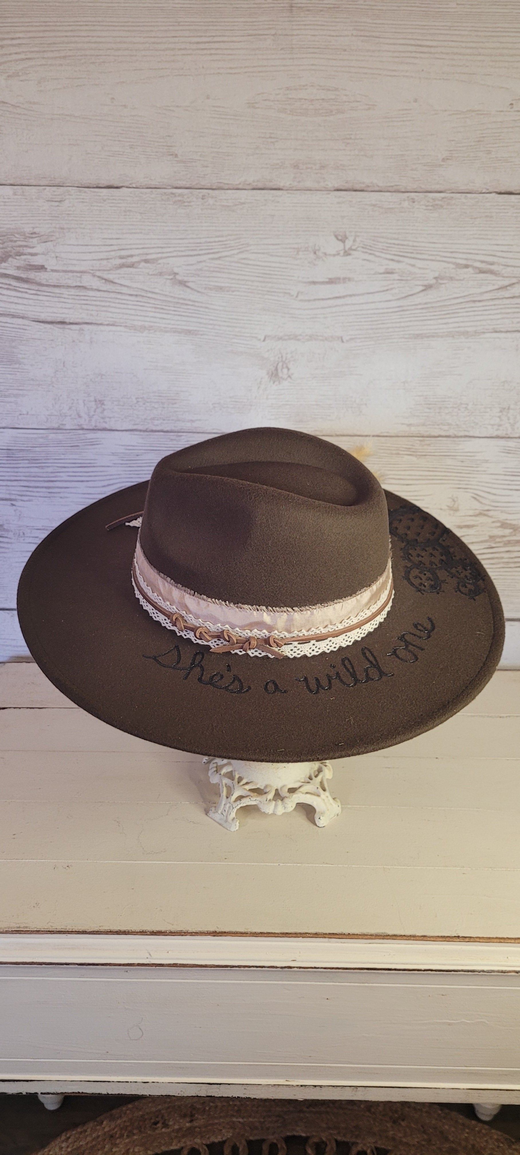 Features "She's a wild one" & cactus engraving Pampas, pine cones, light rose ribbon, natural lace ribbon, leather band Felt hat Flat brim 65% polyester and 35% cotton Ribbon drawstring for hat size adjustment Head Circumference: 24" Crown Height: 5" Brim Length: 15.75" Brim Width: 14.5" Branded & numbered inside crown Custom designed by Kayla