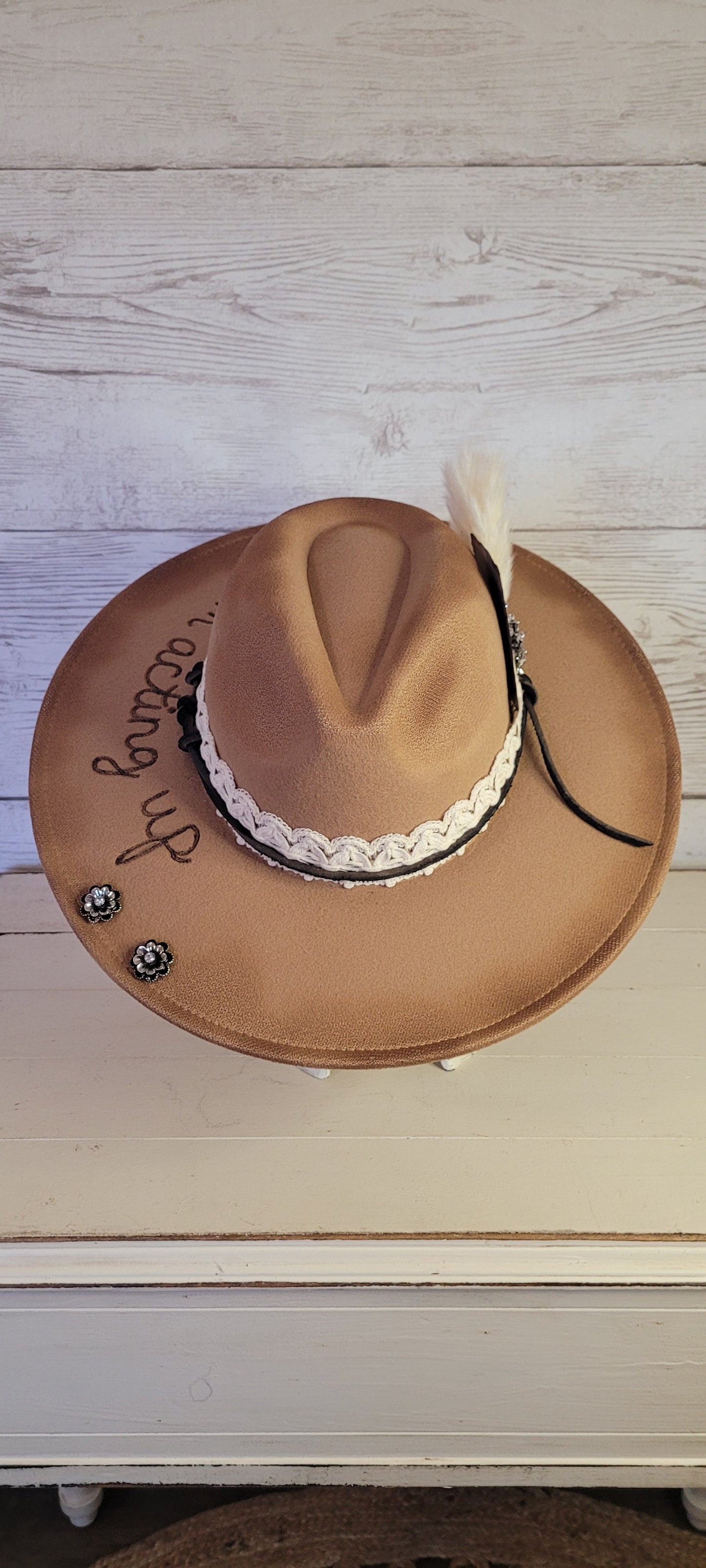 Features "I'm acting up" engraving Lace ribbon, leather band, pampas, rhinestone brooches, playing card Felt hat Flat brim 100% polyester Ribbon drawstring for hat size adjustment Head Circumference: 24" Crown Height: 5" Brim Length: 15.75" Brim Width: 14.5" Branded & numbered inside crown Custom burned & engraved by Kayla