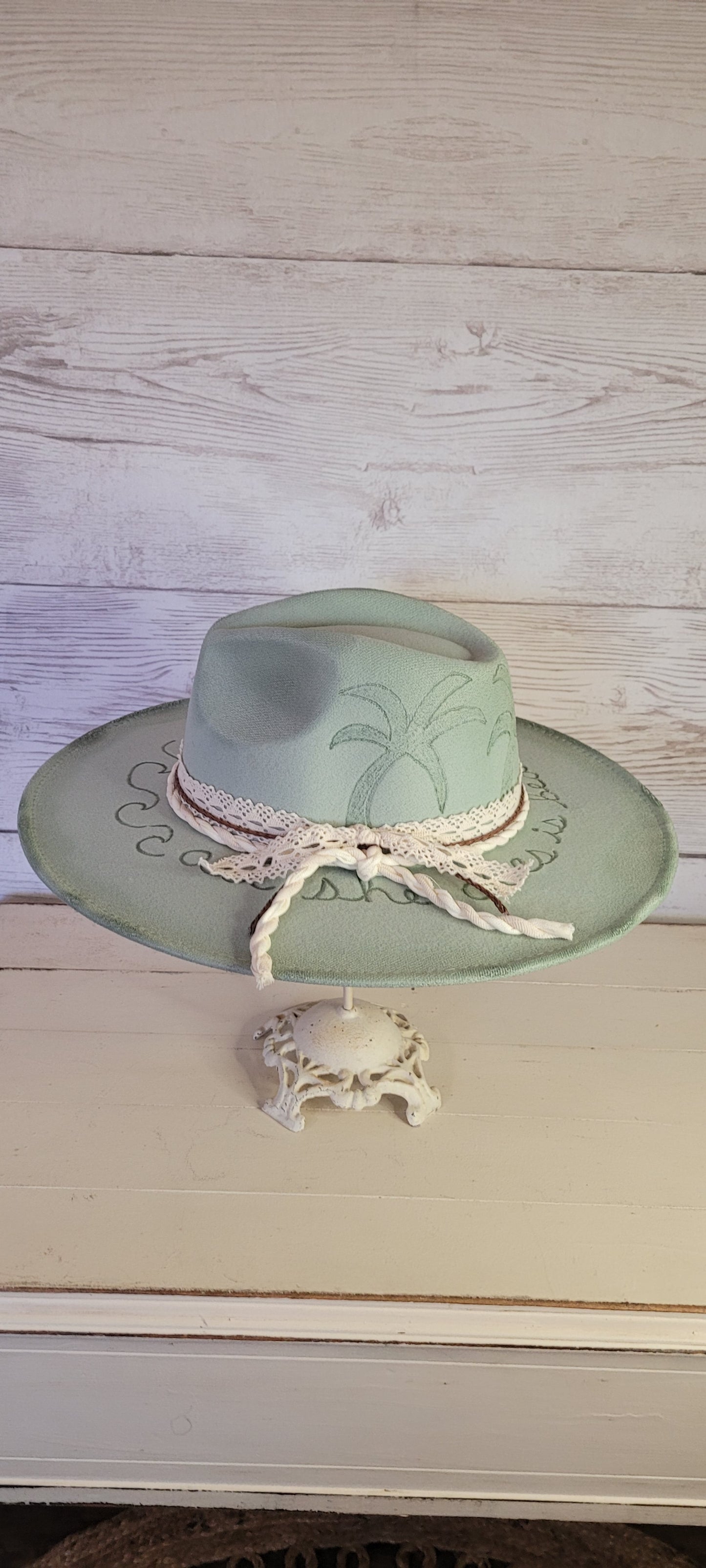 Features sunshine, palm trees, waves & "all she does is beach, beach, beach" engraved Lace ribbon, brown cord, & natural gauze rope Felt hat Flat brim 65% polyester and 35% cotton Ribbon drawstring for hat size adjustment Head Circumference: 24" Crown Height: 5" Brim Length: 15.75" Brim Width: 14.5" Branded & numbered inside crown Custom burned & engraved by Kayla
