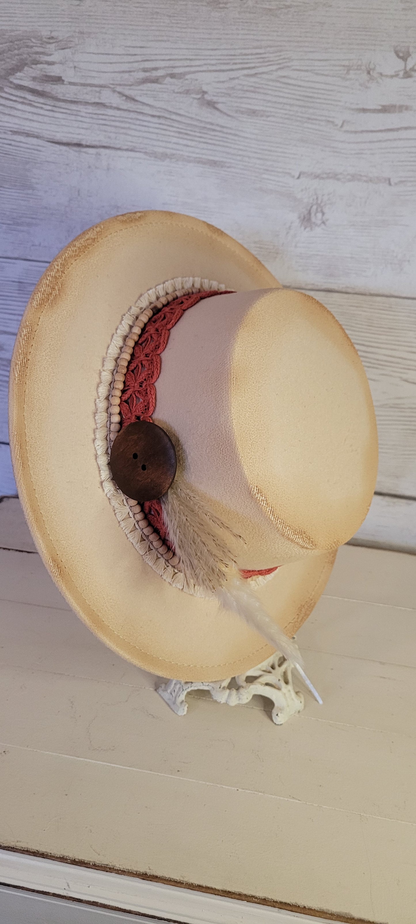 Lace ribbon, tassel ribbon, wooden bead band, button, & pampas Felt hat Flat brim 100% polyester Ribbon drawstring for hat size adjustment Head Circumference: 24" Crown Height: 3.5" Brim Length: 13.5" Brim Width: 12.75" Branded & numbered inside crown Custom burned by Kayla